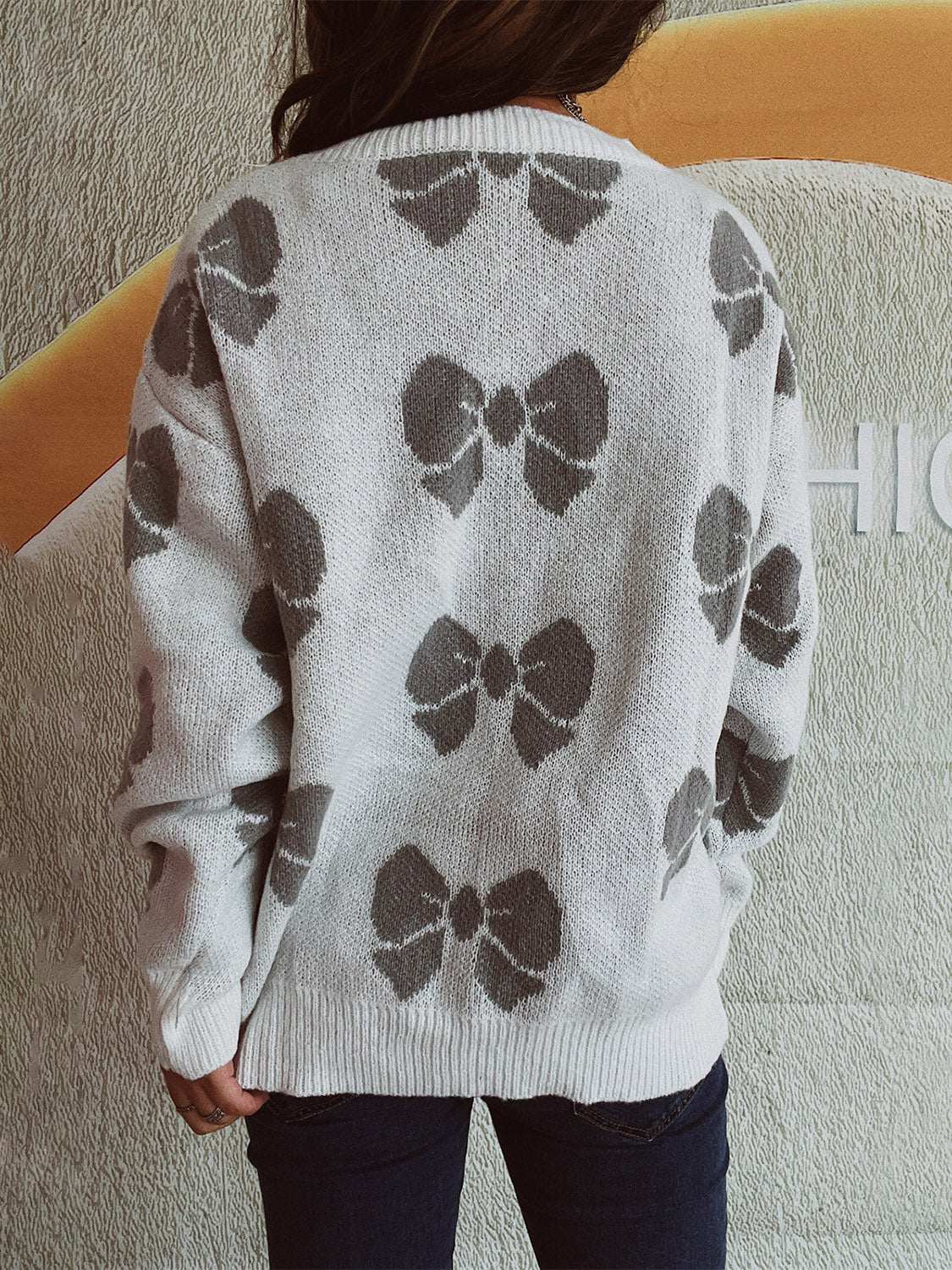 Bow round neck dropped shoulder sweater with gray bow pattern, shown from back.