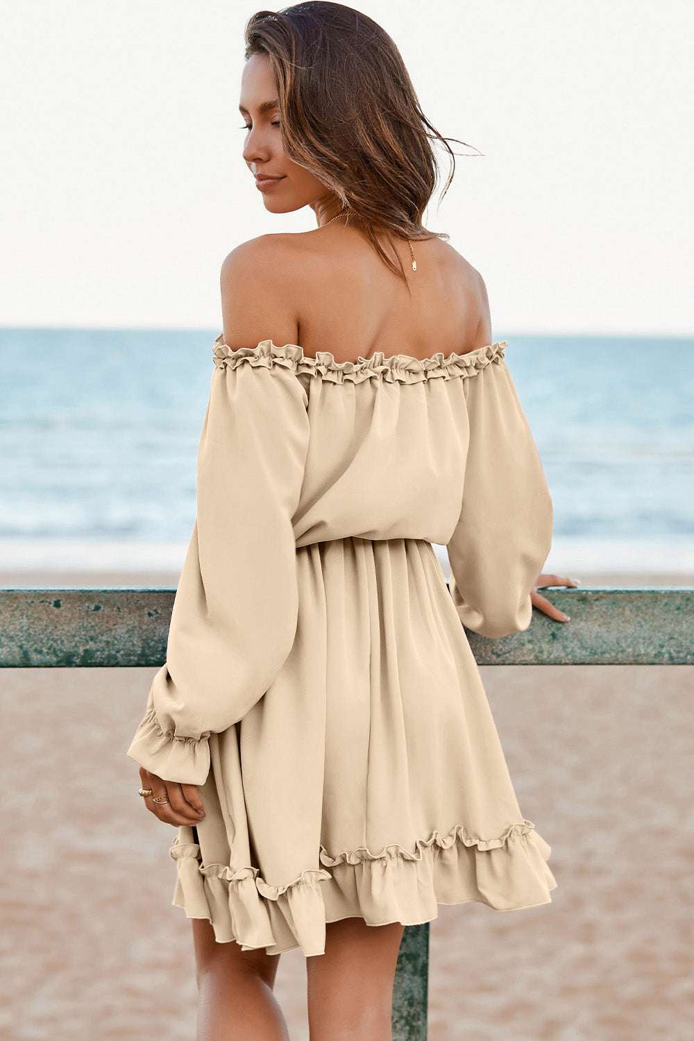 Off-shoulder flounce sleeve dress in beige with frill detail, beach background.