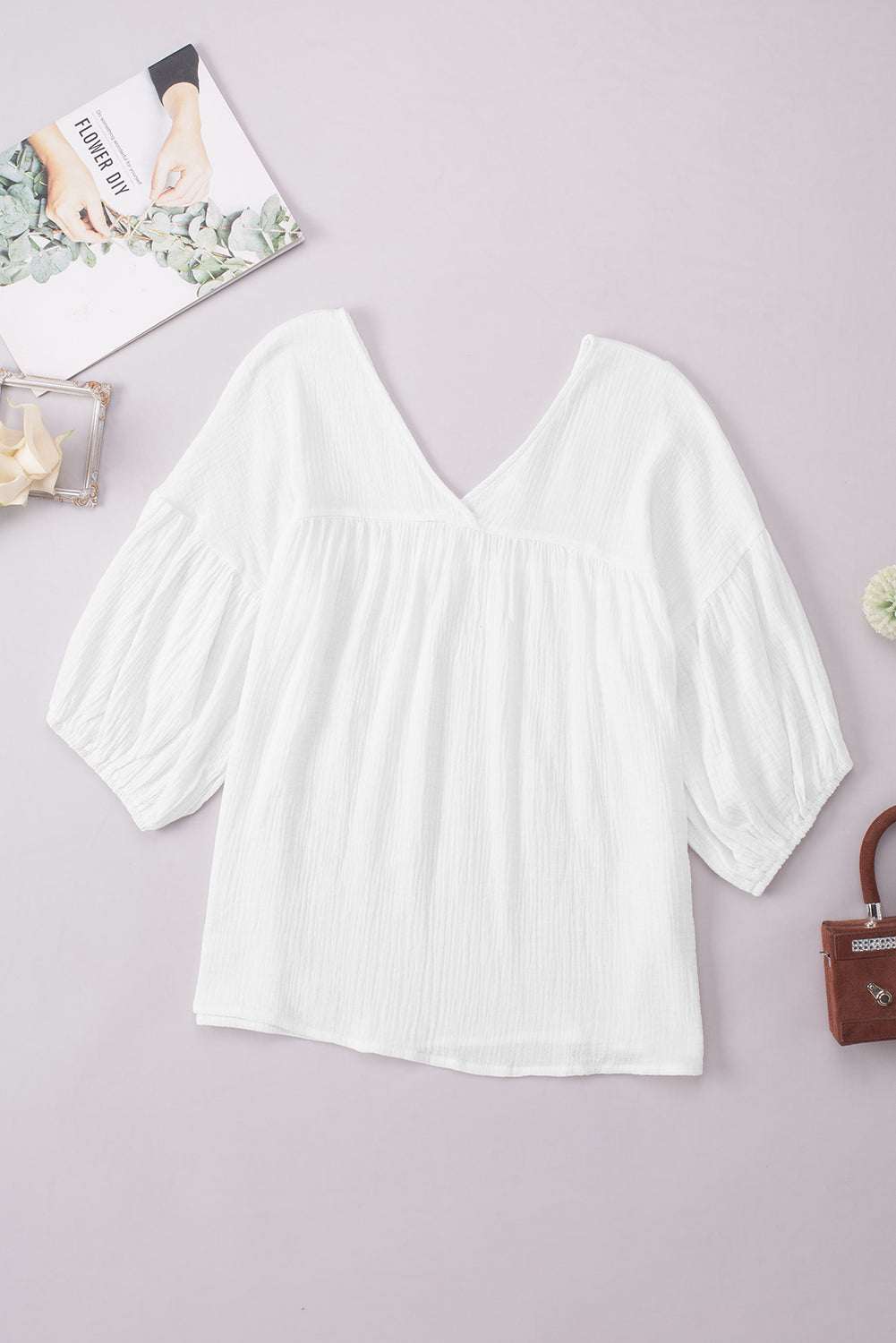 Casual solid white V-neck blouse with long, dropped shoulder sleeves in 100% cotton.