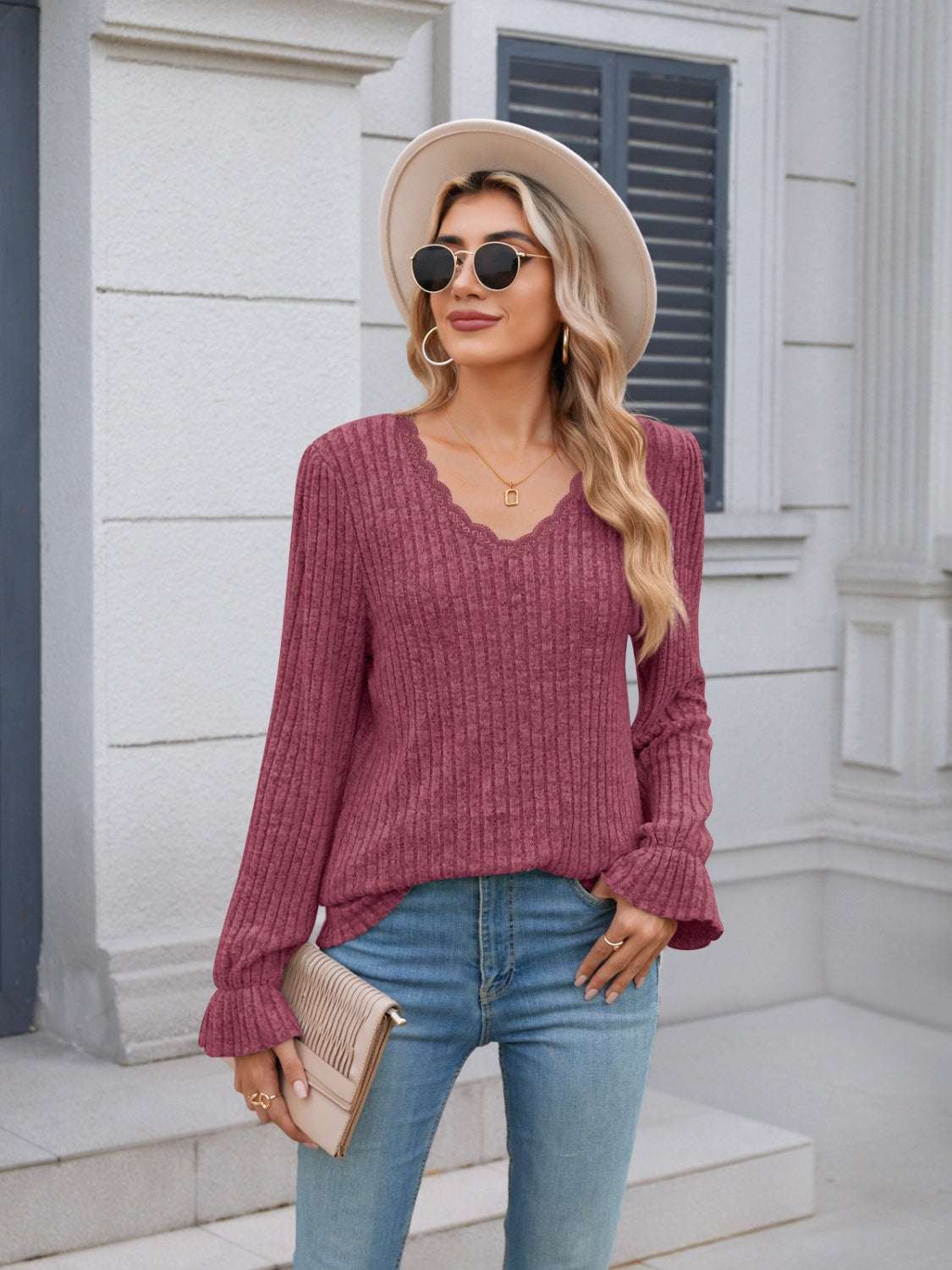 Lace detail V-neck long sleeve T-shirt in pink with ruffled sleeves, worn by a woman outdoors.