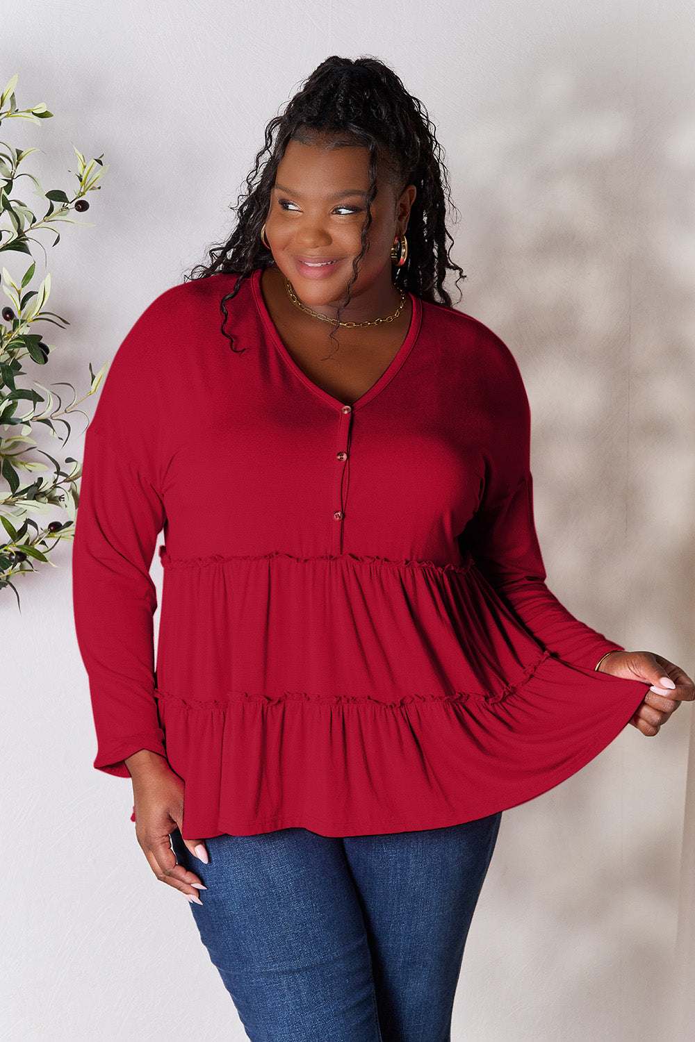 Curve model wearing a red half button long sleeve ruffle hem blouse.