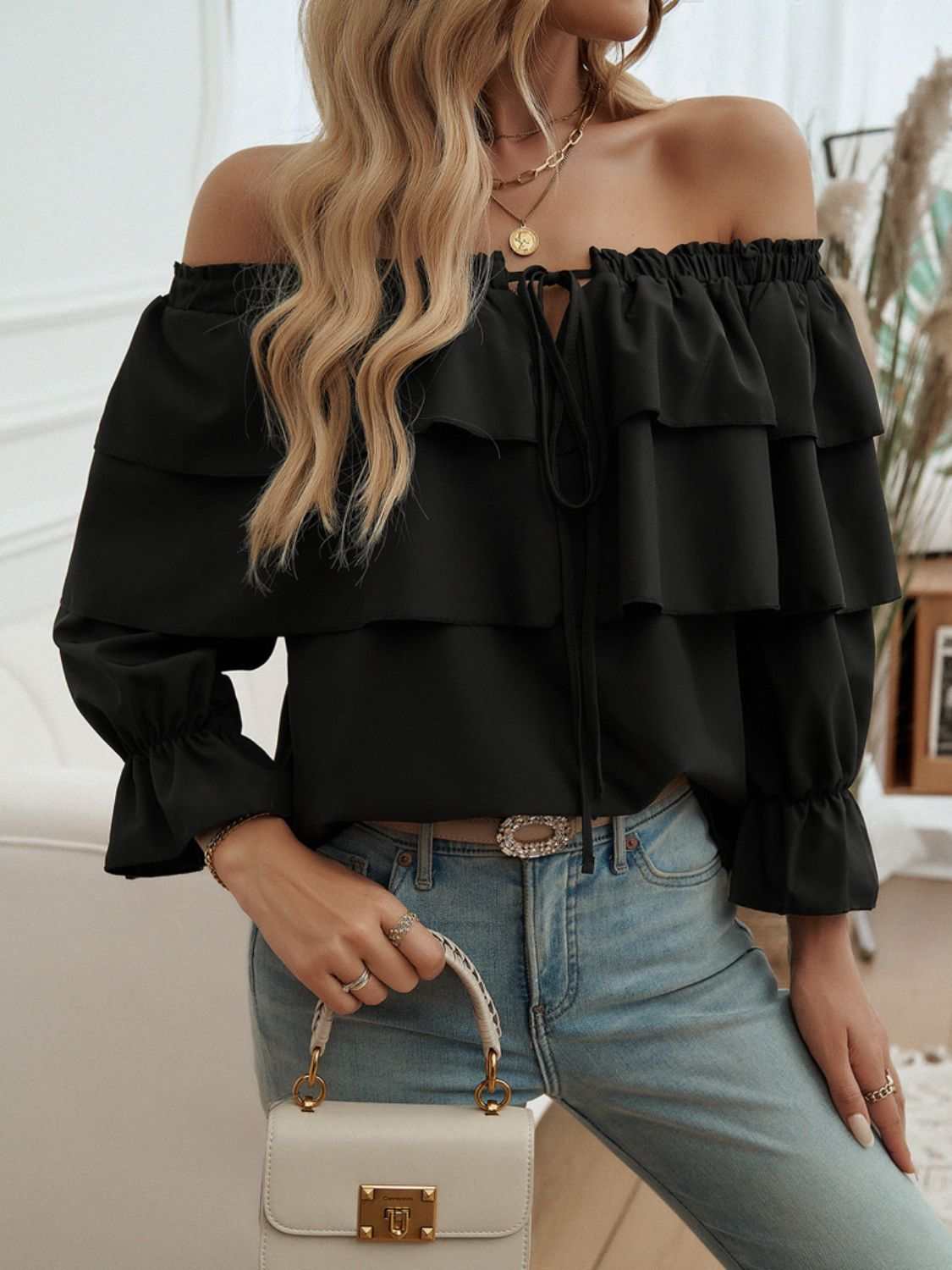 Off-shoulder flounce sleeve blouse with drawstring and ruffles, worn with jeans.