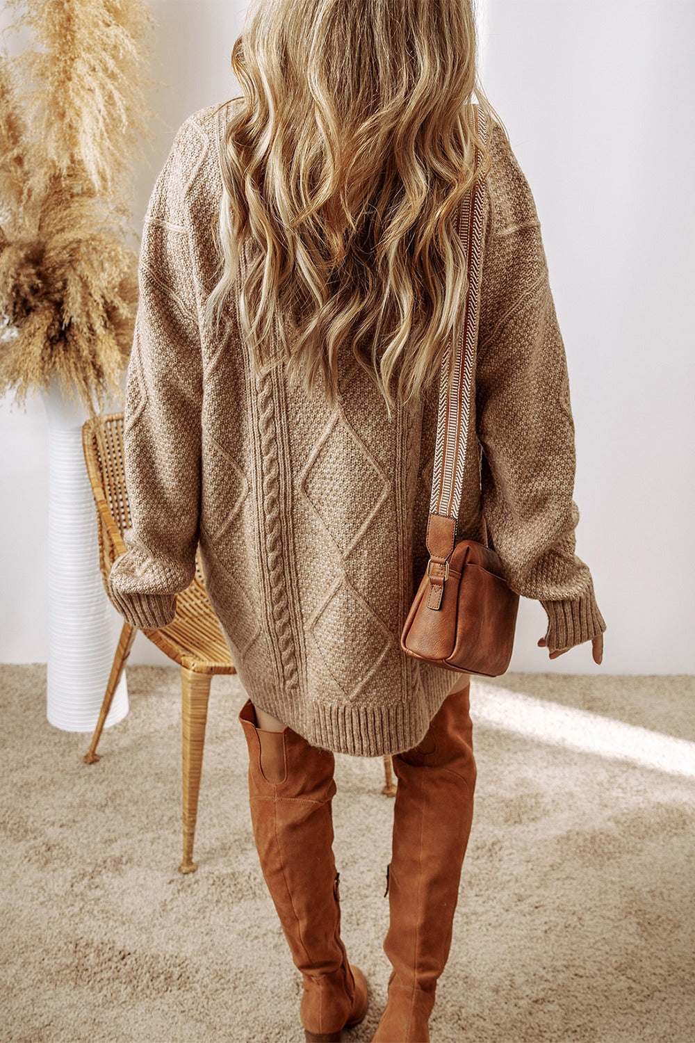Cable-knit round neck sweater dress in beige, slightly stretchy 100% polyester, styled with knee-high boots and a brown purse.