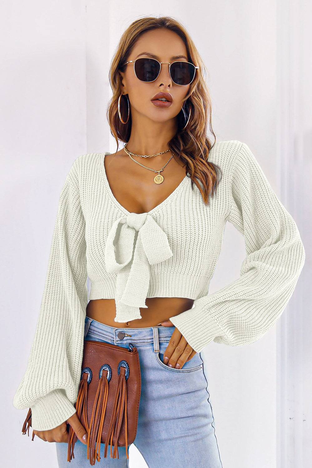 Bow V-Neck Long Sleeve Cropped Sweater in white, featuring a tied front and slightly stretchy material.