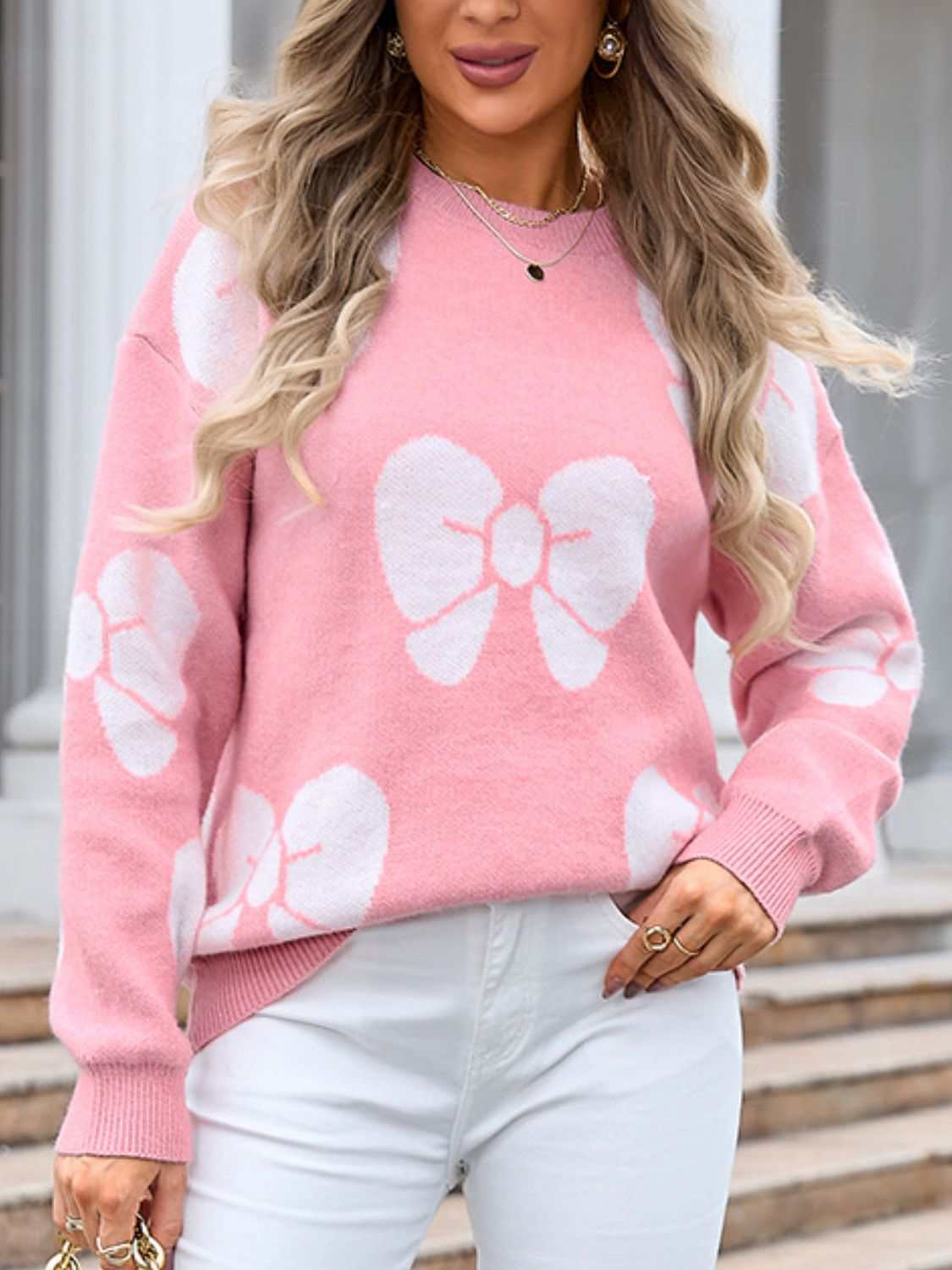 Pink sweater with angel wings bow design, round neck, and dropped shoulders.