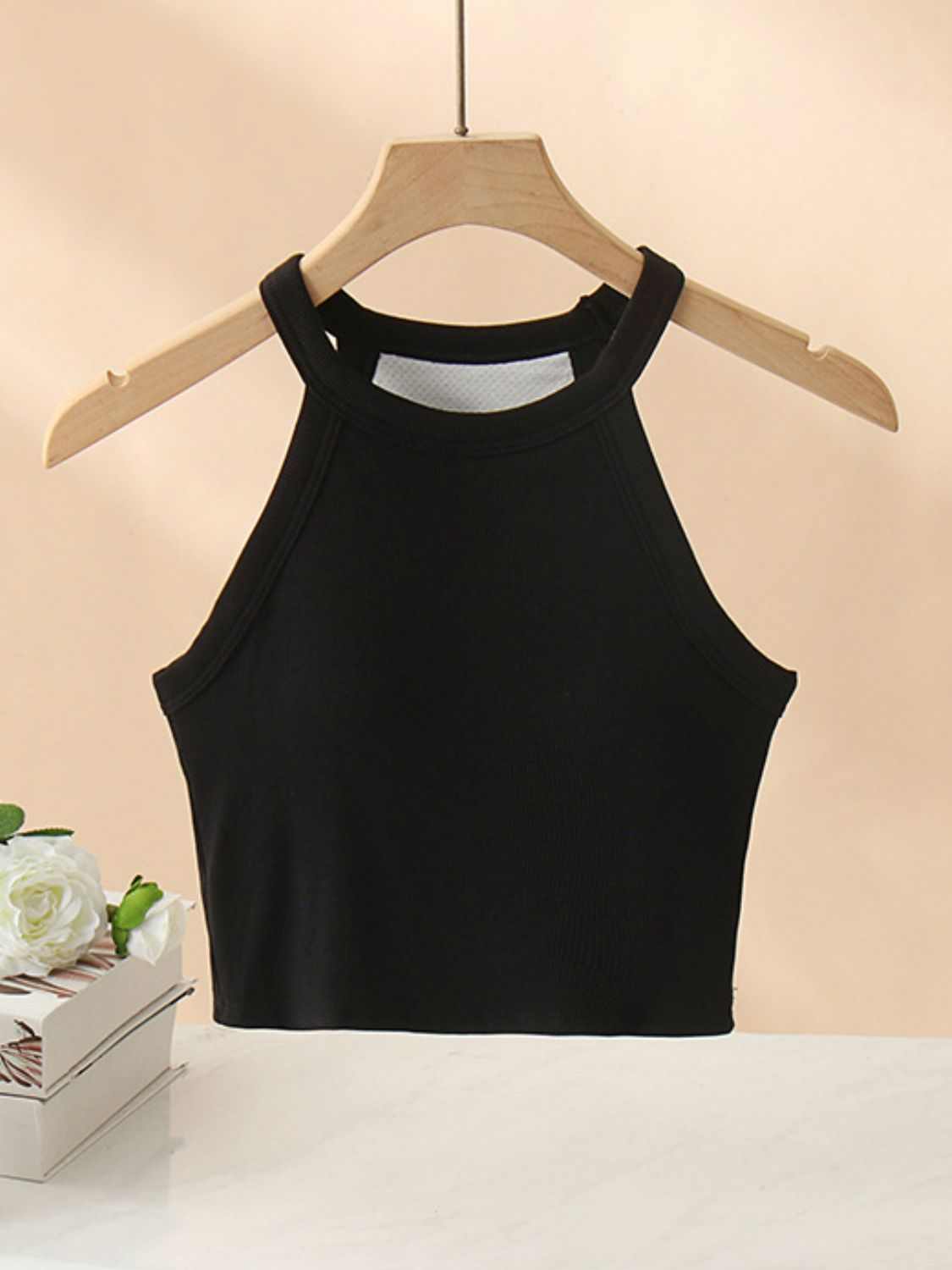 Ribbed Grecian neck cropped tank top with chest pads on hanger.