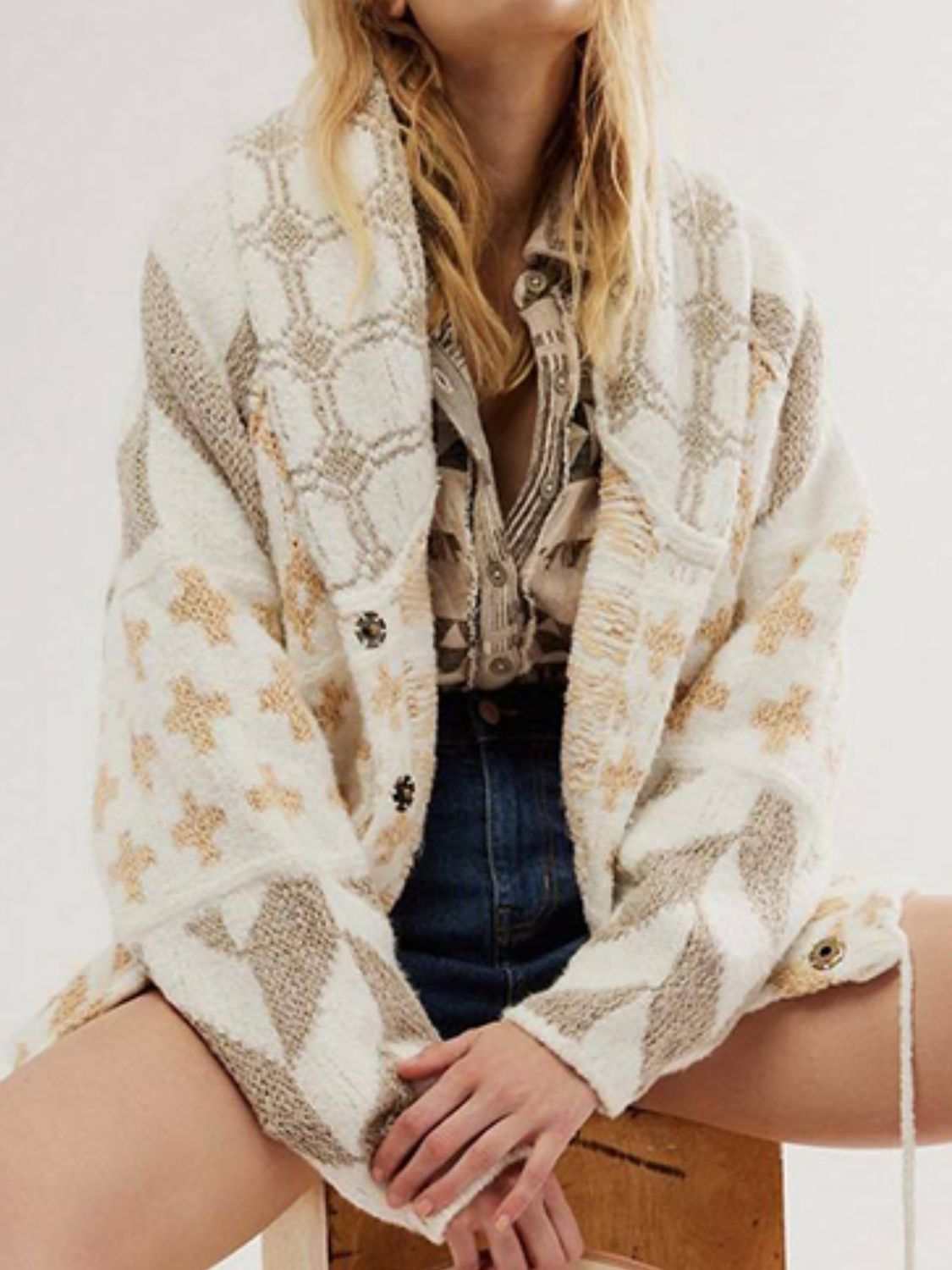 Woman wearing a collared neck long sleeve cardigan with buttoned front and geometric pattern in neutral tones.
