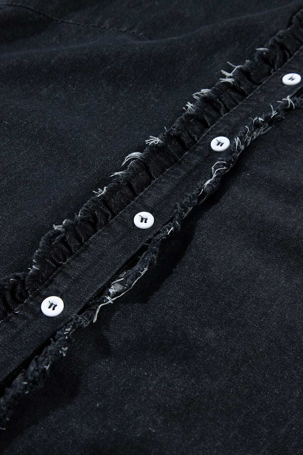 Close-up of a black button down raw hem ruffled denim shirt, showcasing button detail and frayed edges.