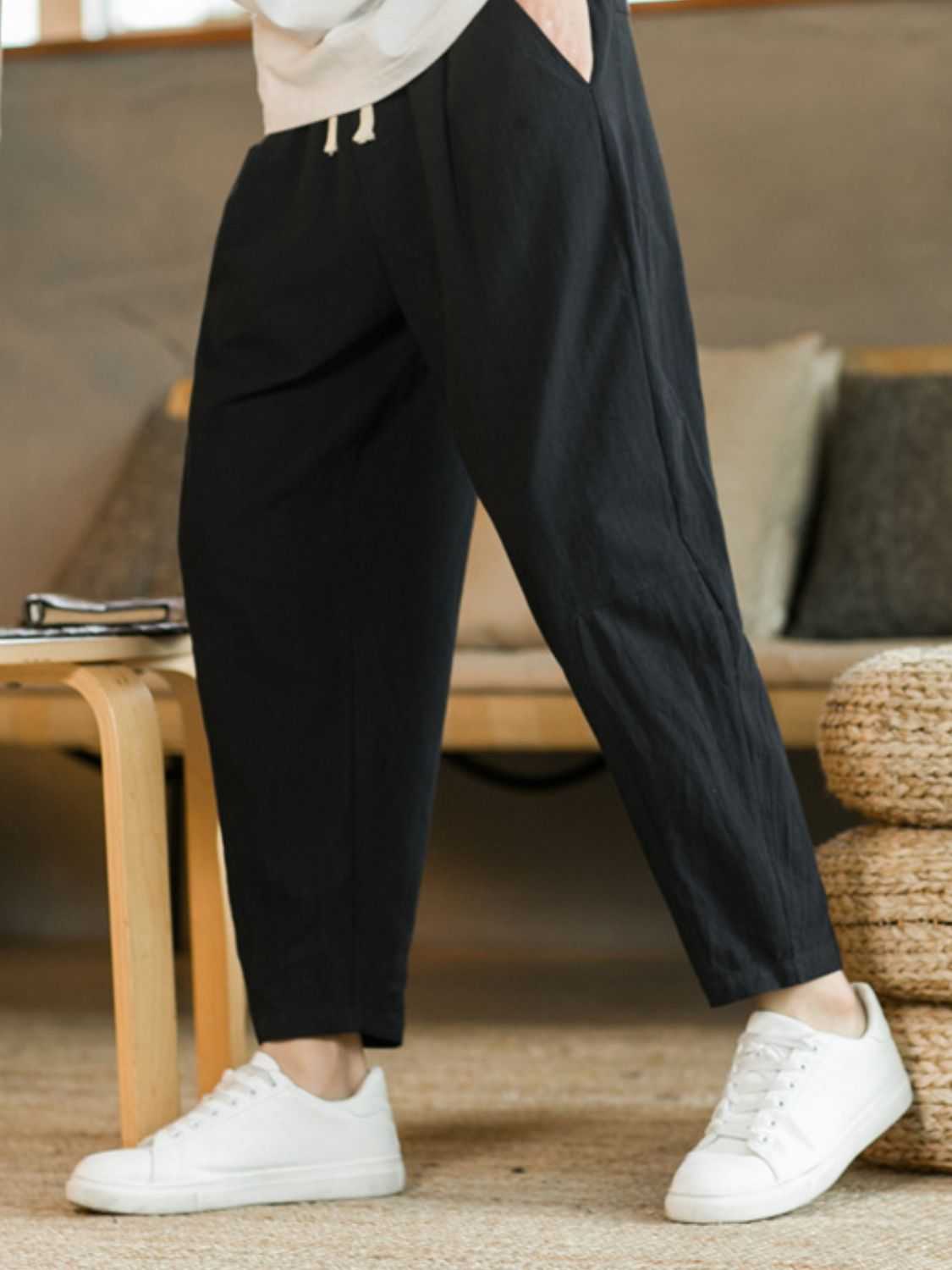 Plus size black drawstring pants with pockets and white sneakers.