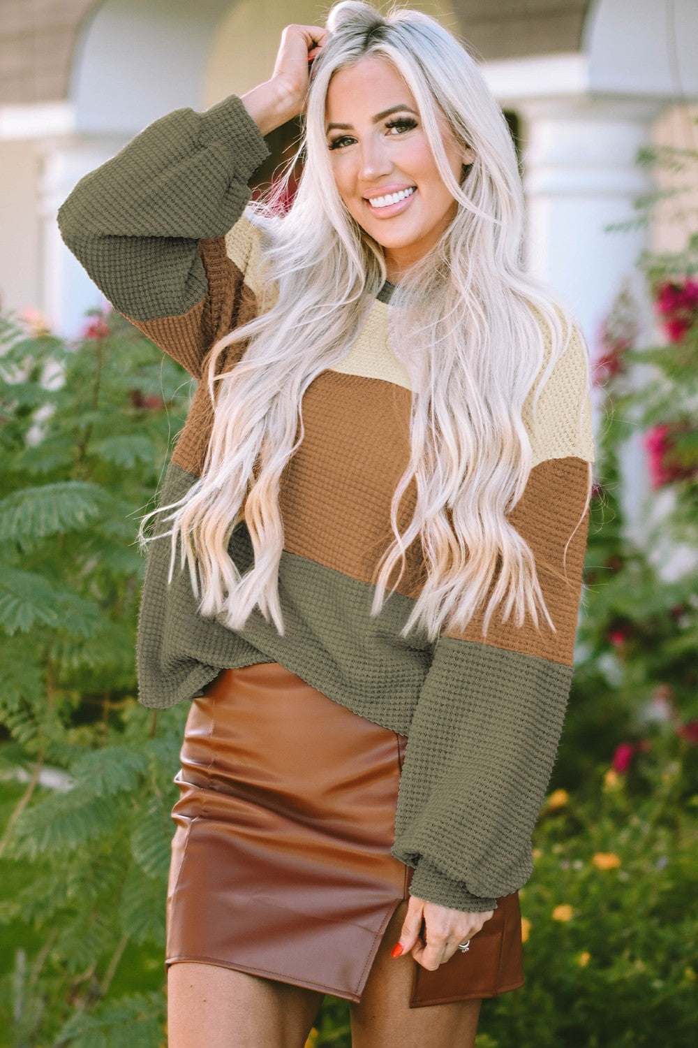 Woman wearing waffle-knit color block round neck long sleeve blouse with brown leather skirt outdoors