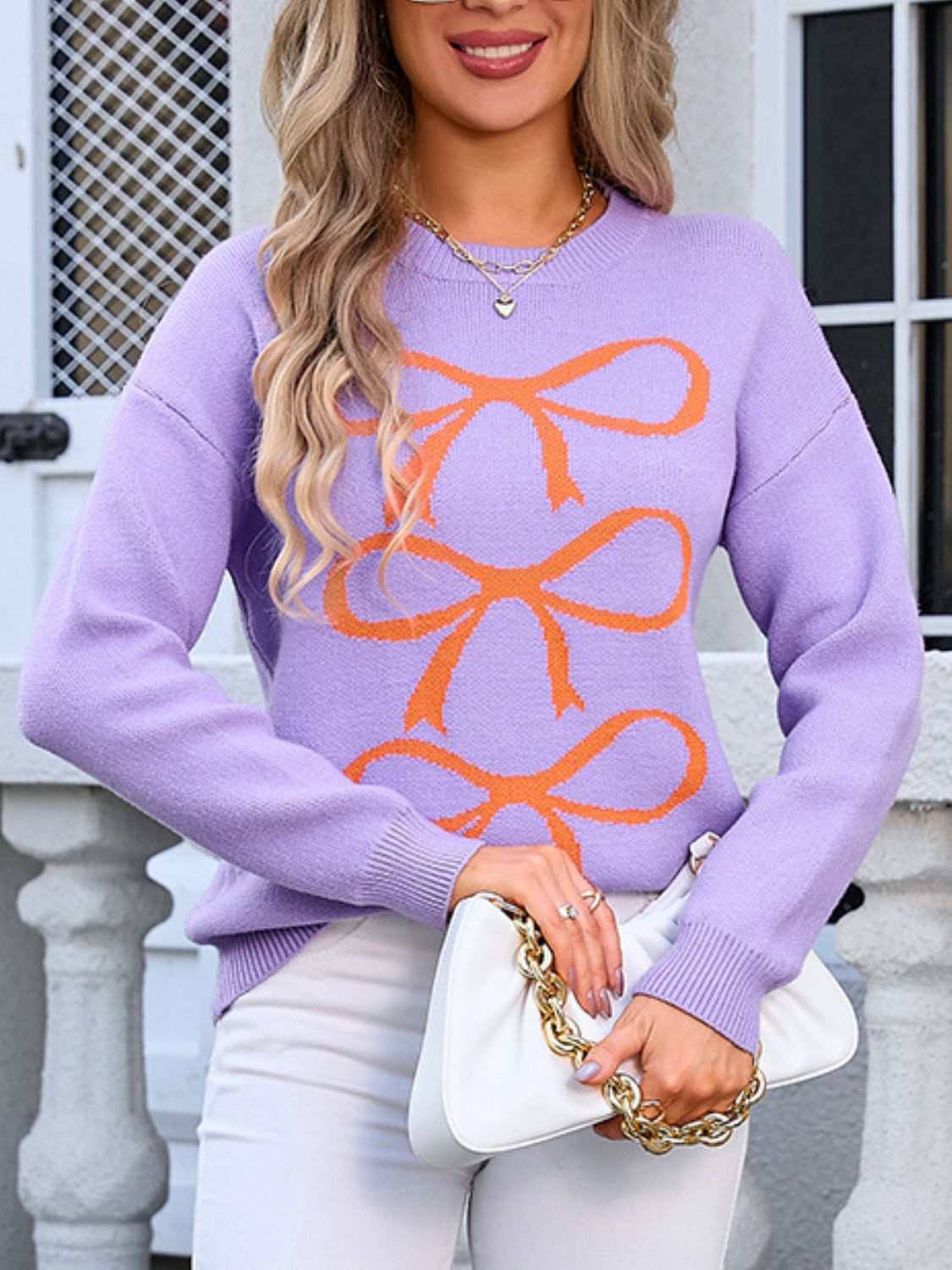 Purple sweater with orange angel wings bow graphic, round neck, and long sleeves.