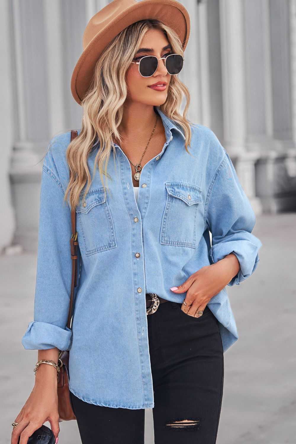 Woman wearing a light blue collared neck dropped shoulder denim top with buttoned front and pockets, styled casually with rolled sleeves and black ripped jeans.