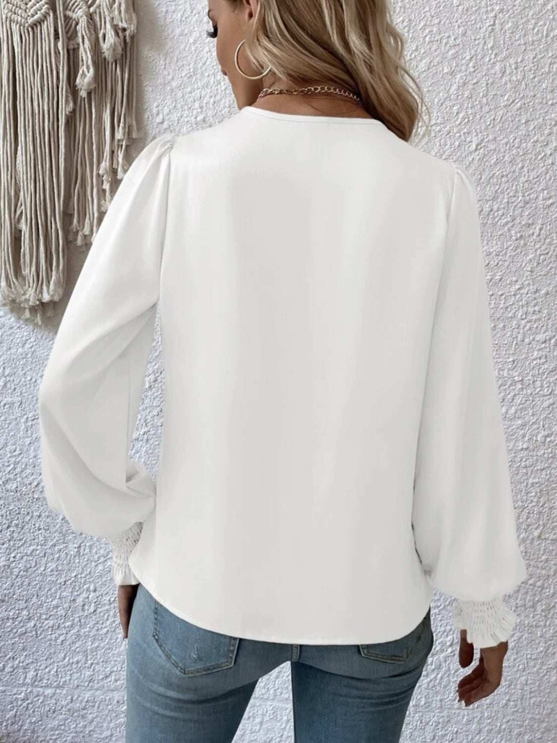 White surplice smocked lantern sleeve blouse, polyester, worn by model, back view.