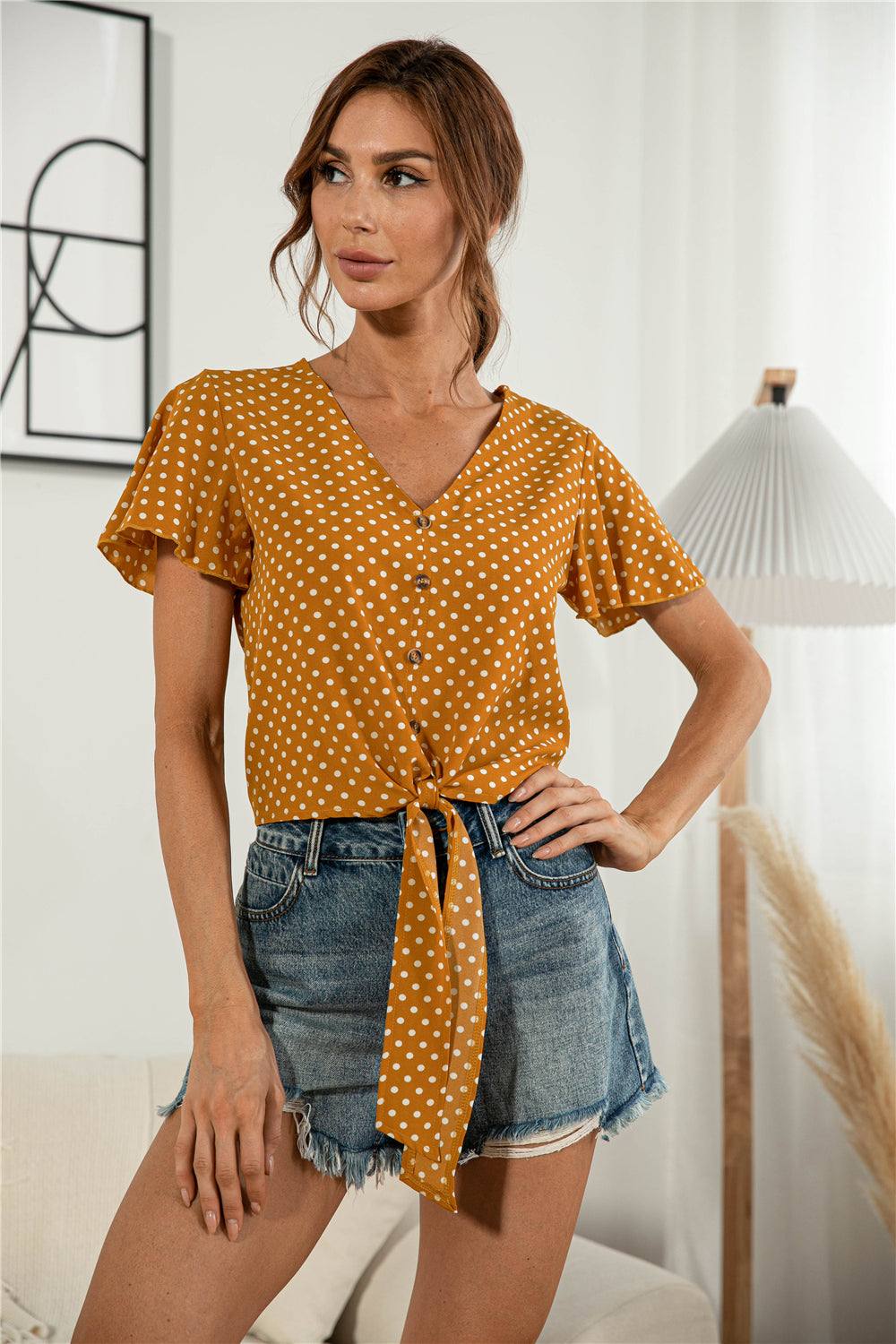 Casual V-neck tied blouse with short flutter sleeves and button details.
