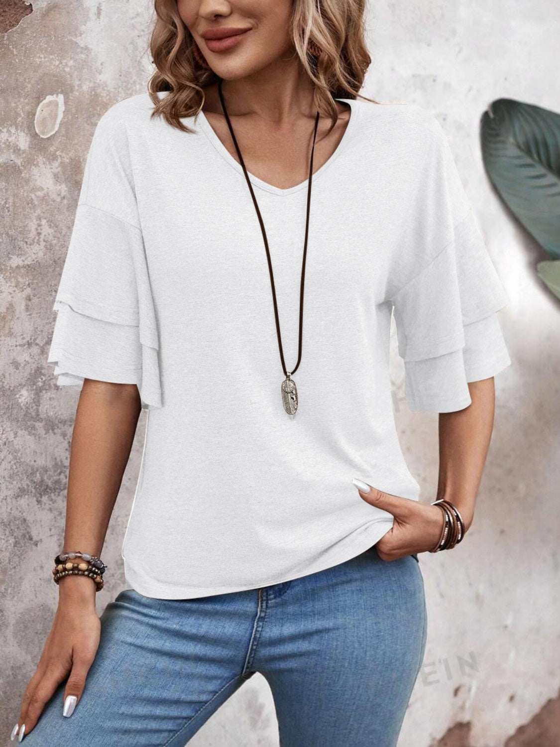 V-Neck half sleeve blouse in white polyester-rayon blend, styled with jeans and accessories.