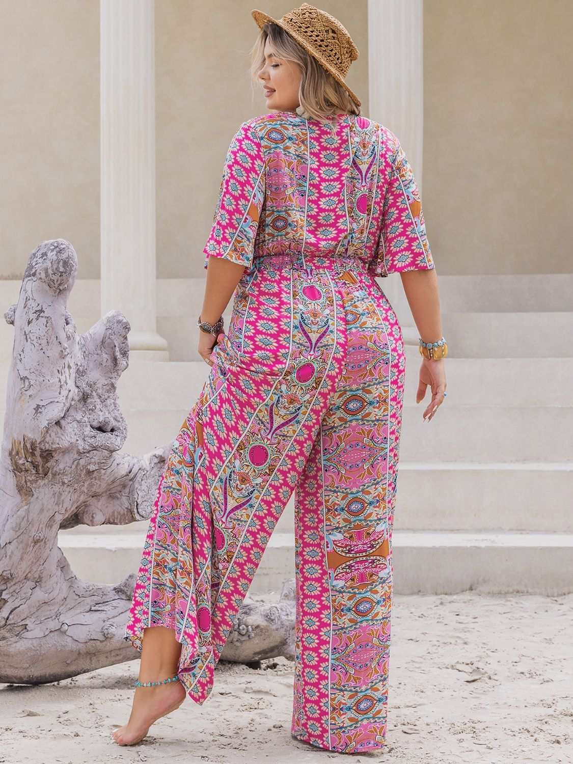 Plus size printed half sleeve wide leg jumpsuit in pink with geometric patterns.
