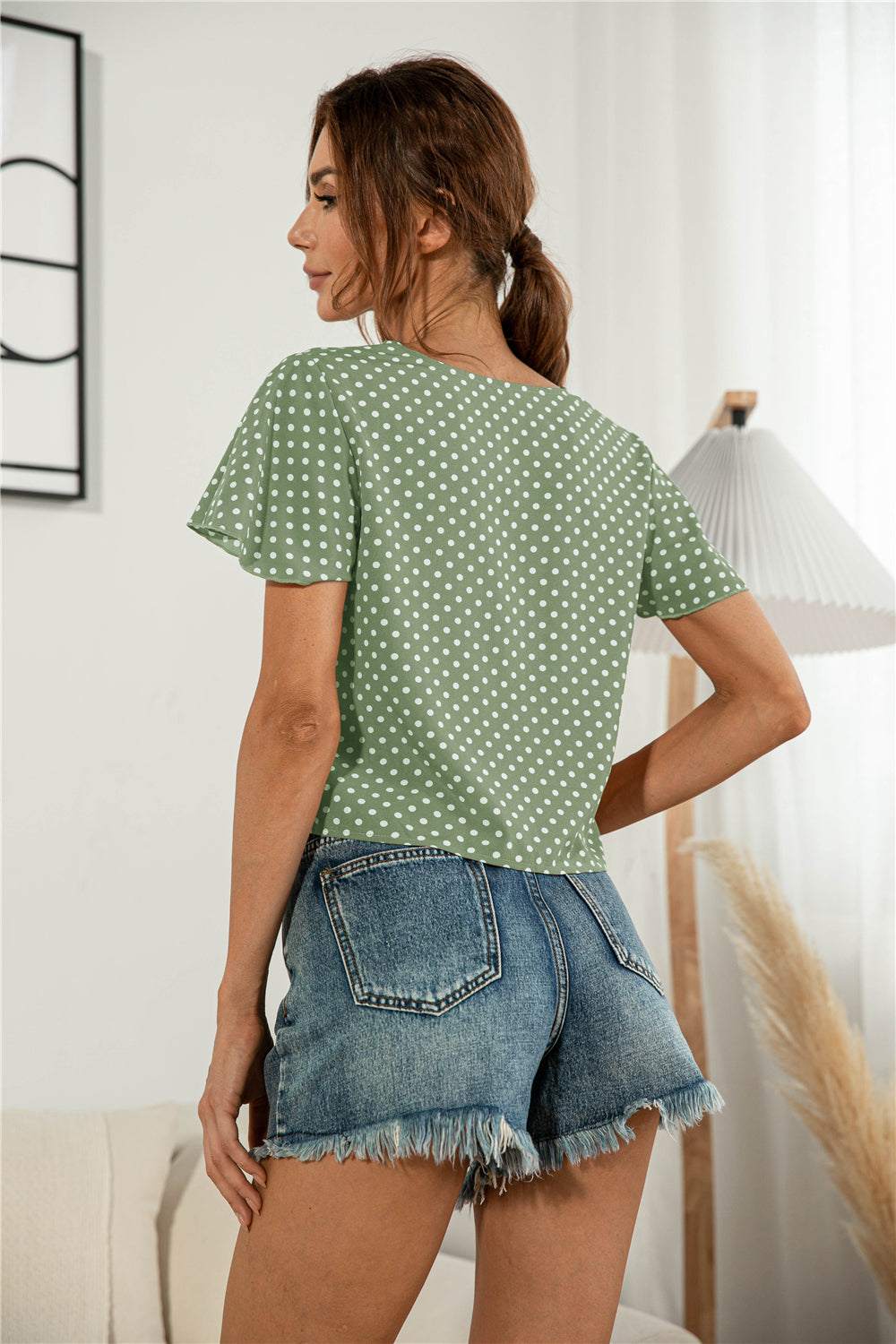 Casual green polka dot V-neck tied blouse with flutter sleeves.