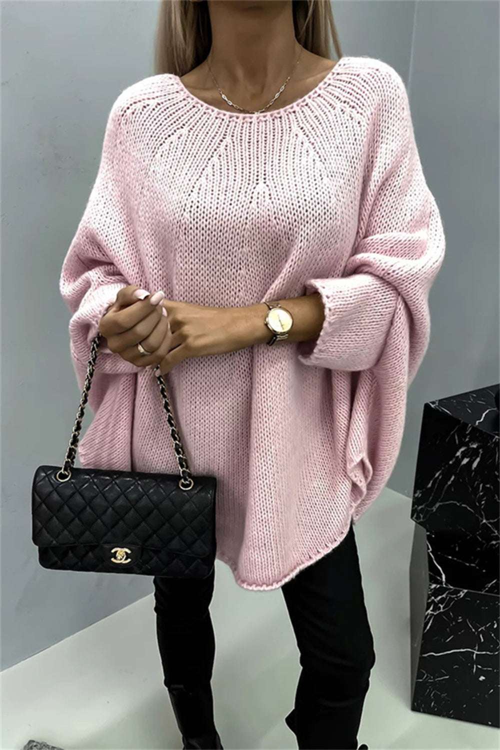 Round Neck Batwing Sleeve Sweater in pink, slightly stretchy polyester, worn by a model holding a black quilted purse.