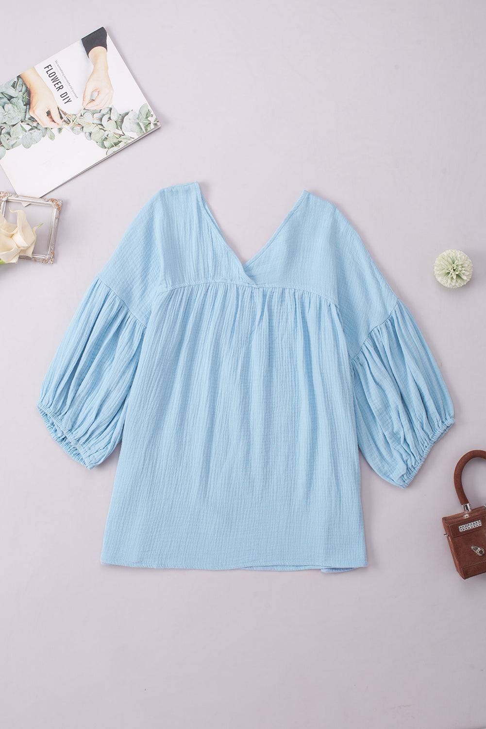 Light blue dropped shoulder V-neck blouse with long sleeves and casual style.