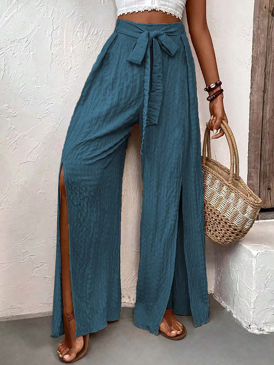Wide leg pants with side slits in blue, featuring a tie waist detail.