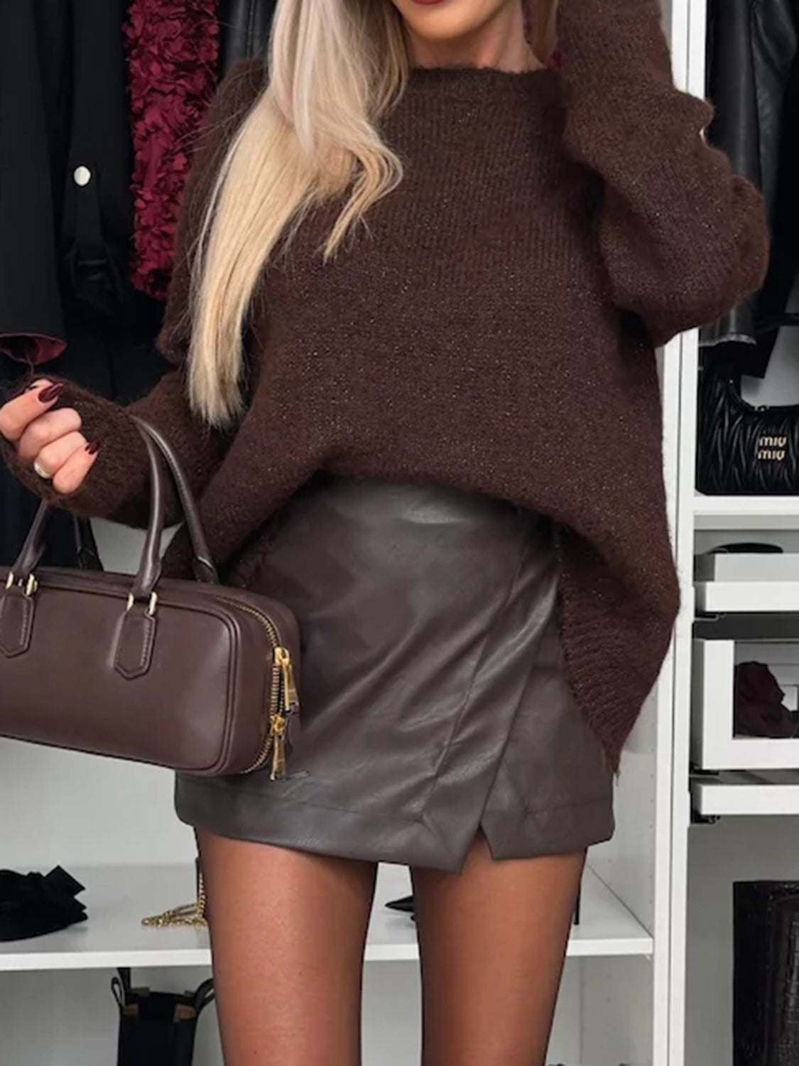 Bow slit back round neck sweater in brown, paired with a leather skirt and handbag.