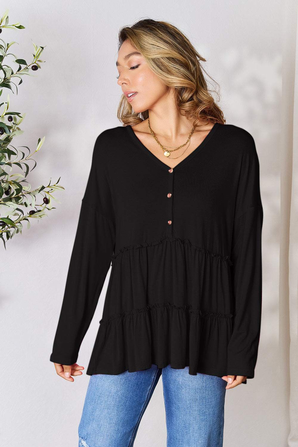 Half button long sleeve ruffle hem blouse in black, featuring a buttoned front and layered ruffle design.