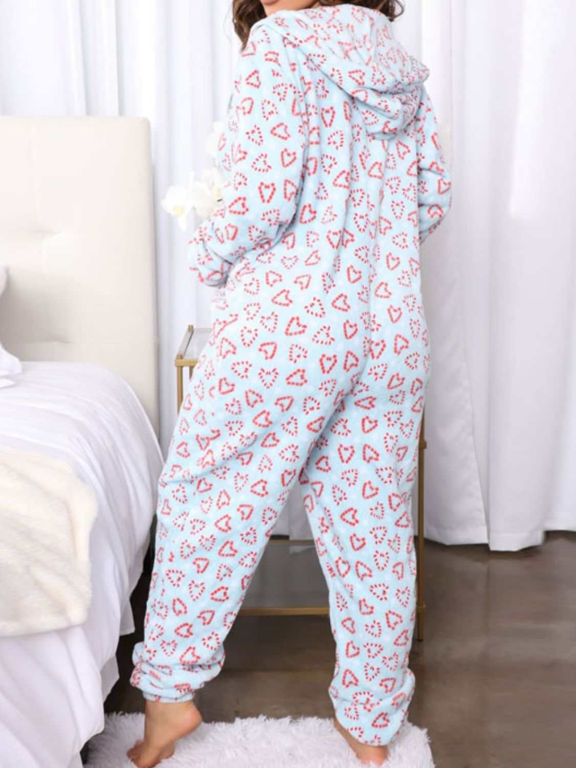 Printed zip-up long sleeve hooded lounge jumpsuit with pockets and heart pattern.