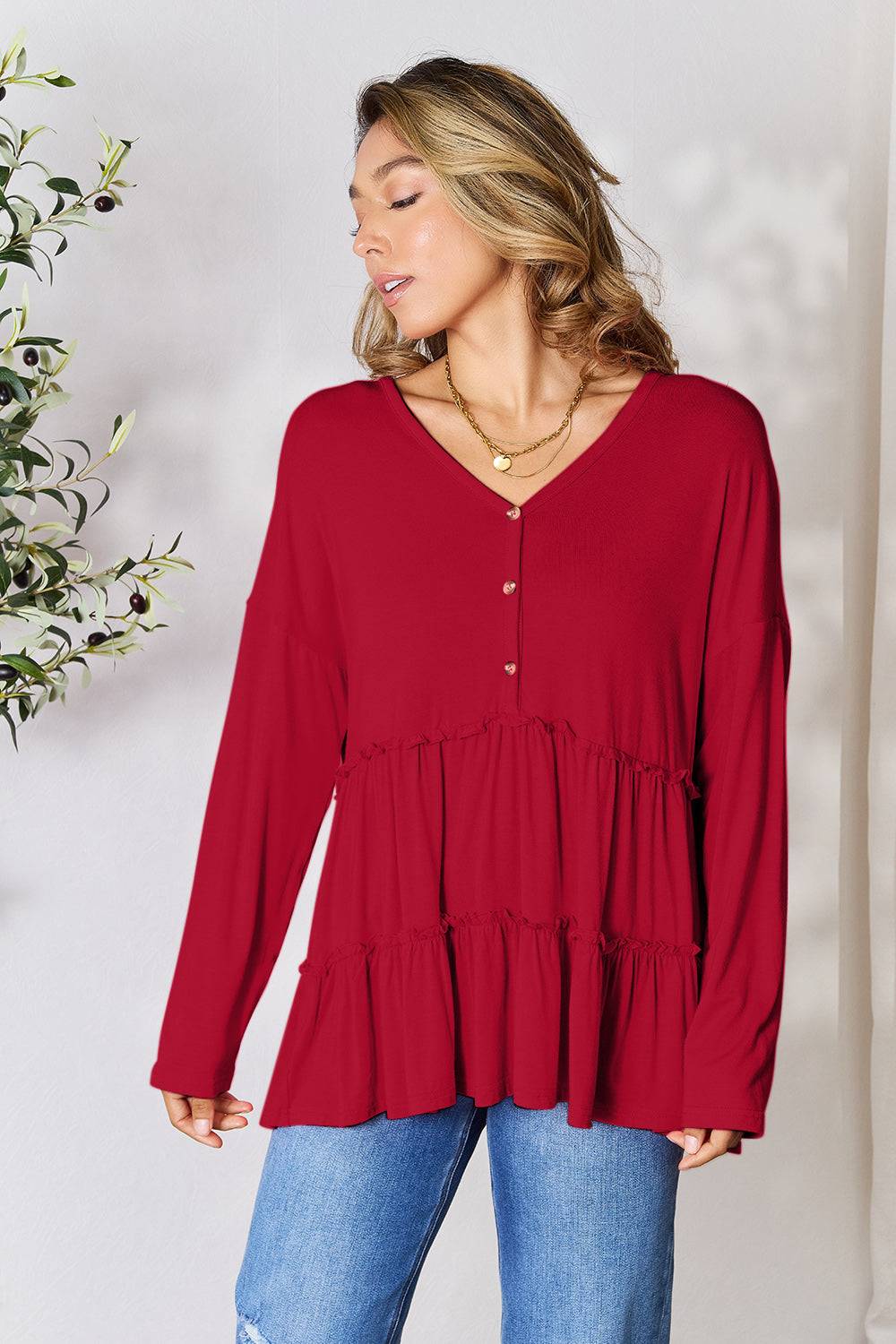 Red half button long sleeve ruffle hem blouse with v-neckline, paired with blue jeans.