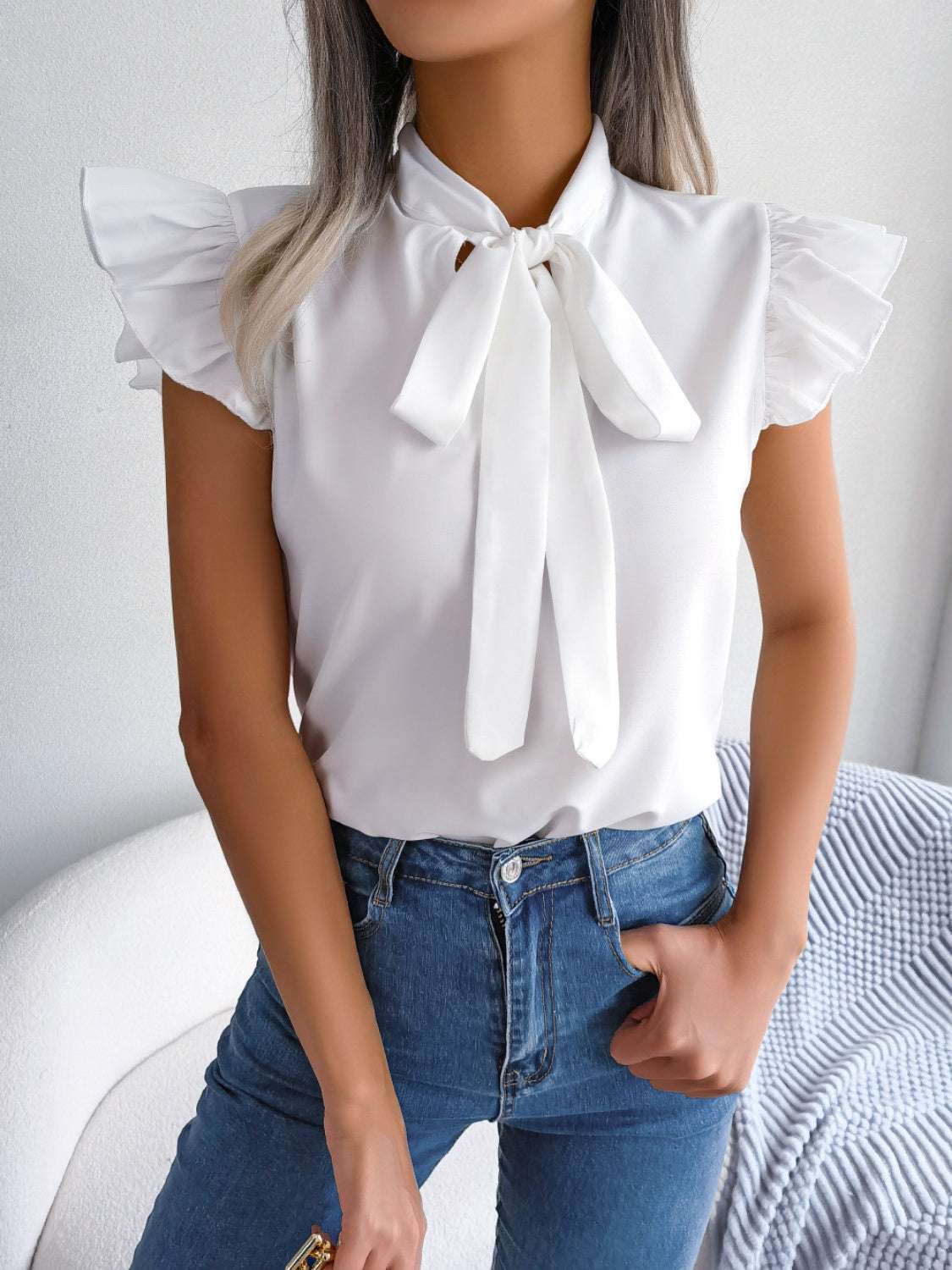 Tie neck cap sleeve blouse in white with tied design, slightly stretchy polyester-elastane material.