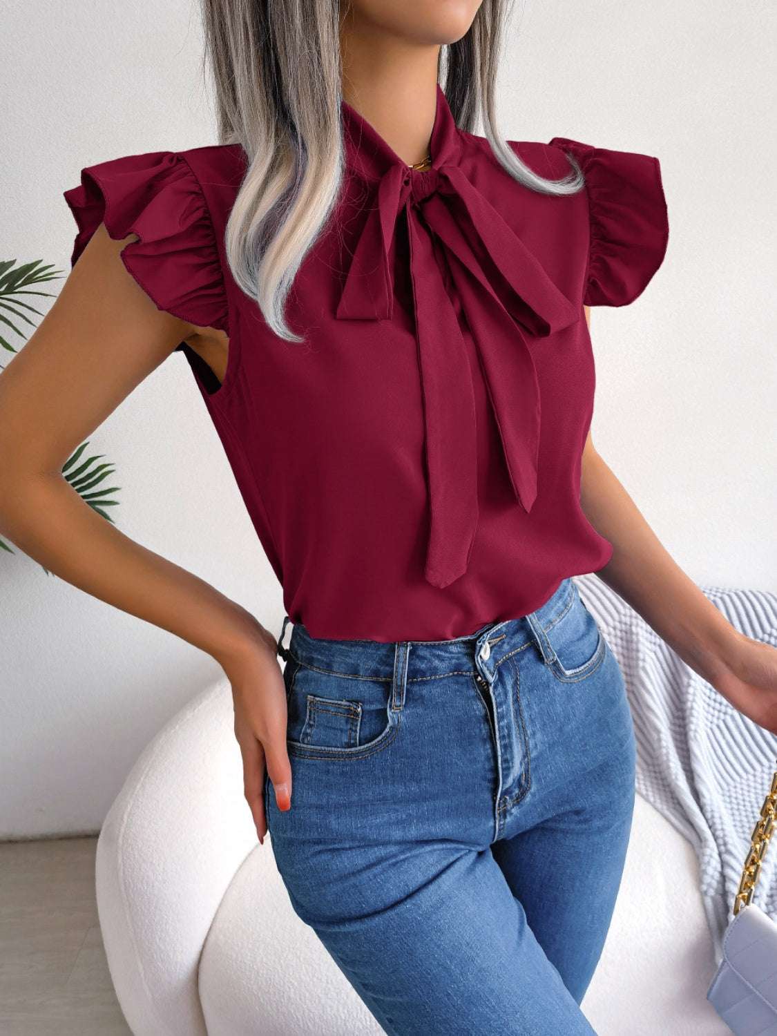 Tie neck cap sleeve blouse in burgundy with slightly stretchy, opaque fabric.