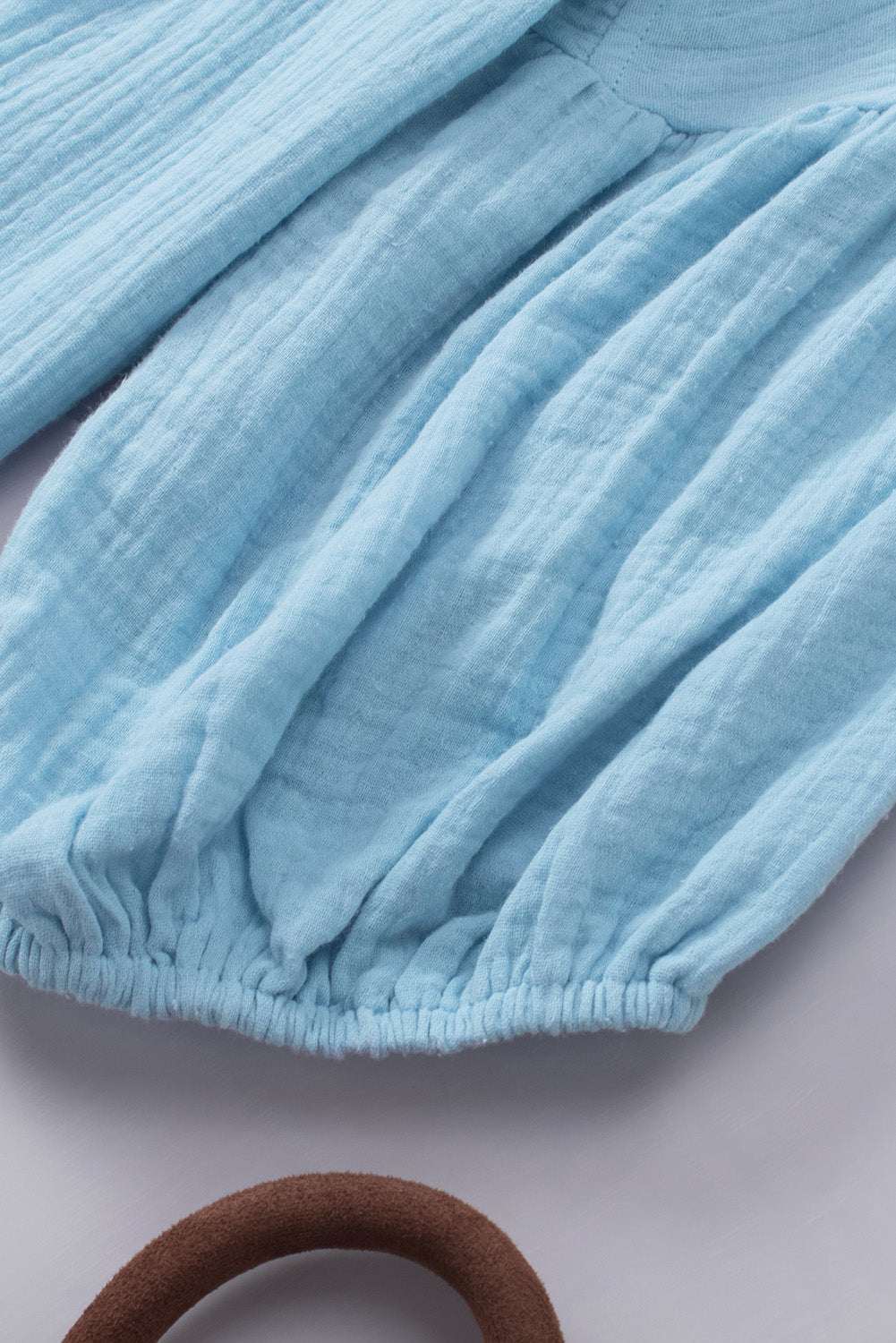 Light blue dropped shoulder V-neck blouse with long sleeves and gathered cuffs.