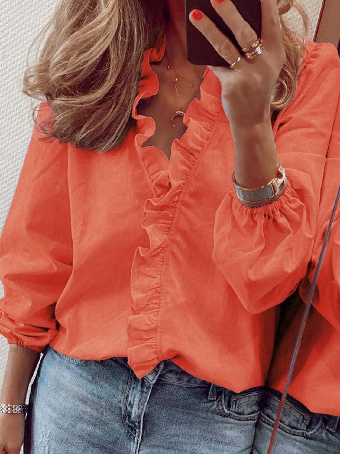 Ruffled V-neck long sleeve blouse in bright orange, worn by model.