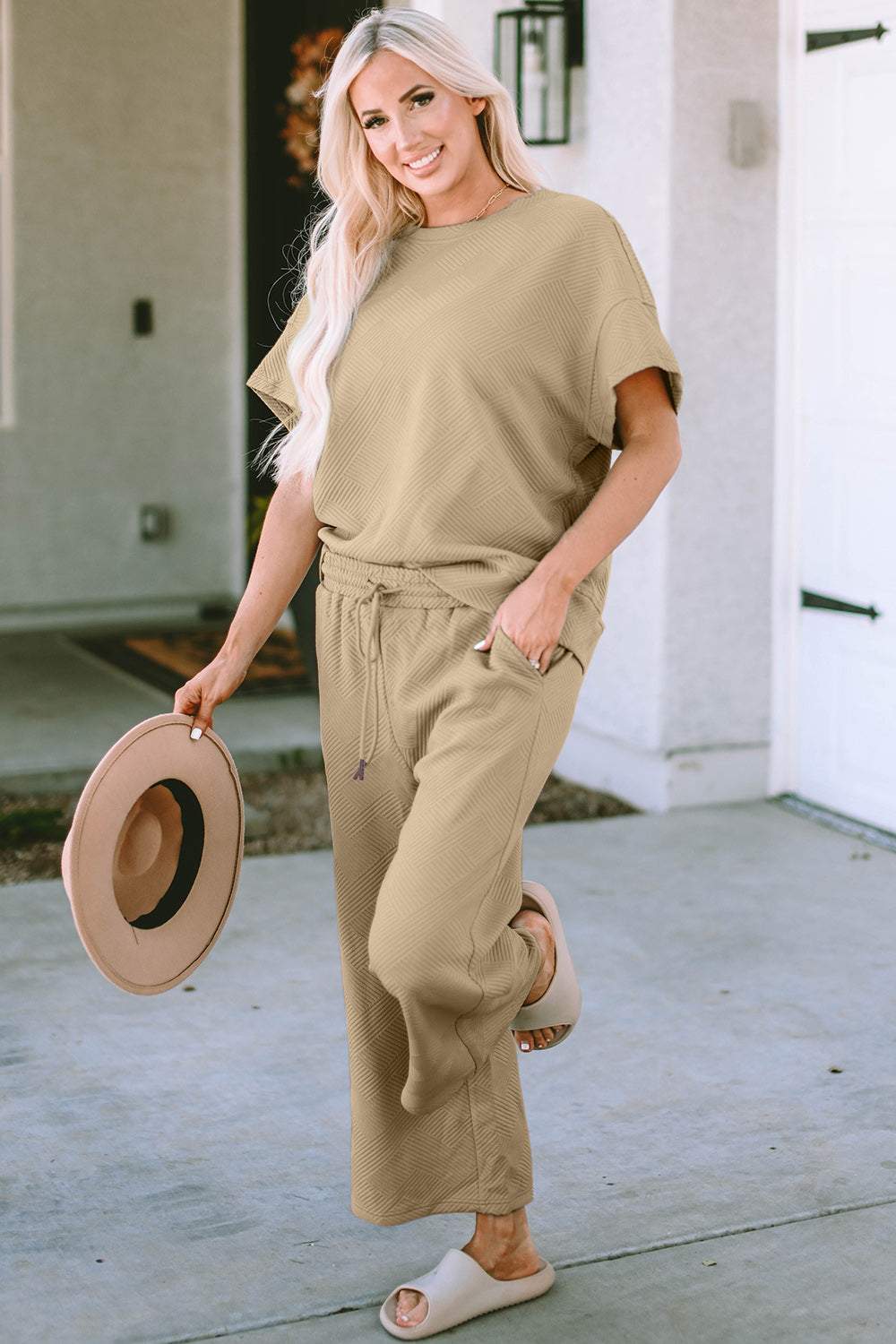 Woman wearing a full-size texture short sleeve top and pants set with a drawstring waist.