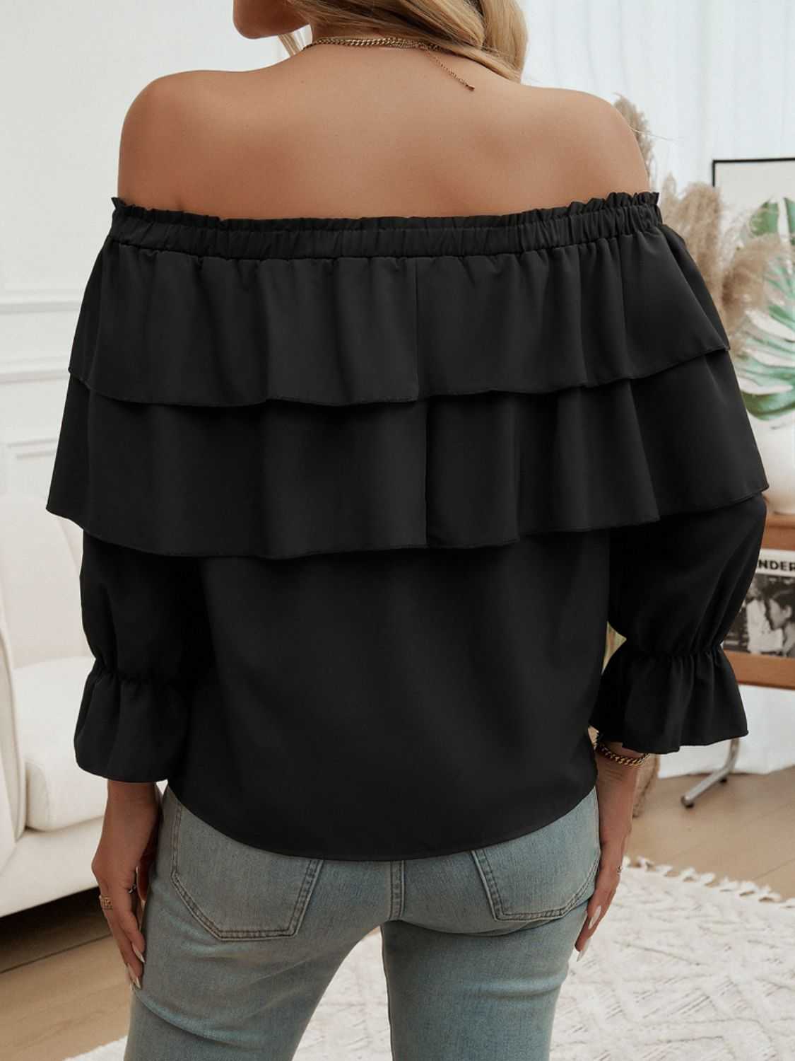 Off-shoulder flounce sleeve blouse in black with ruffled design.