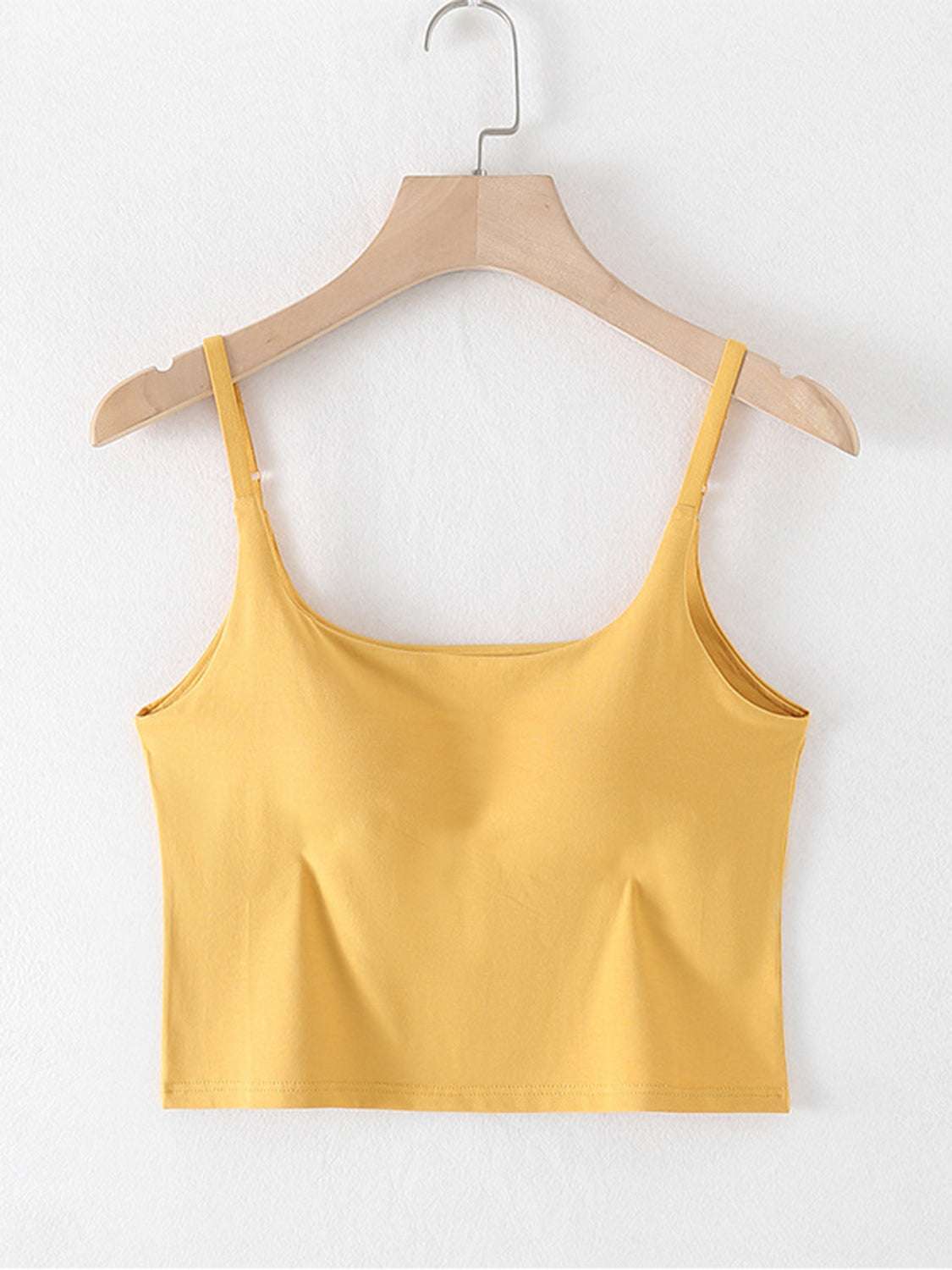 Scoop neck cropped cami in yellow with chest pads on a hanger.