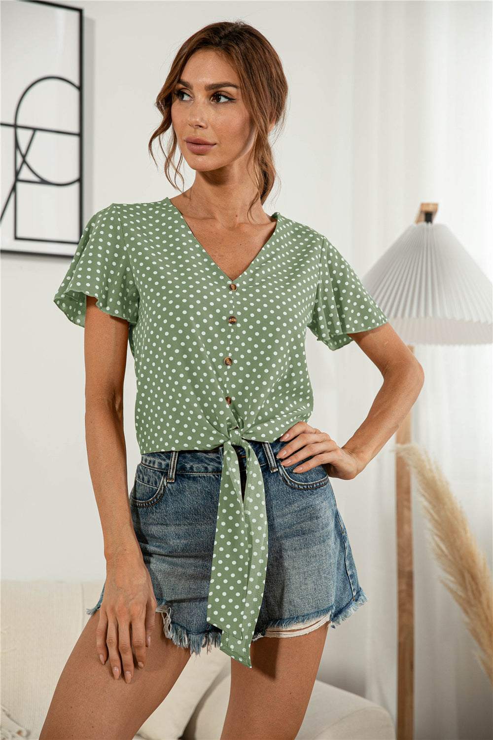 Decorative button V-neck tied blouse with short flutter sleeves in a casual style.