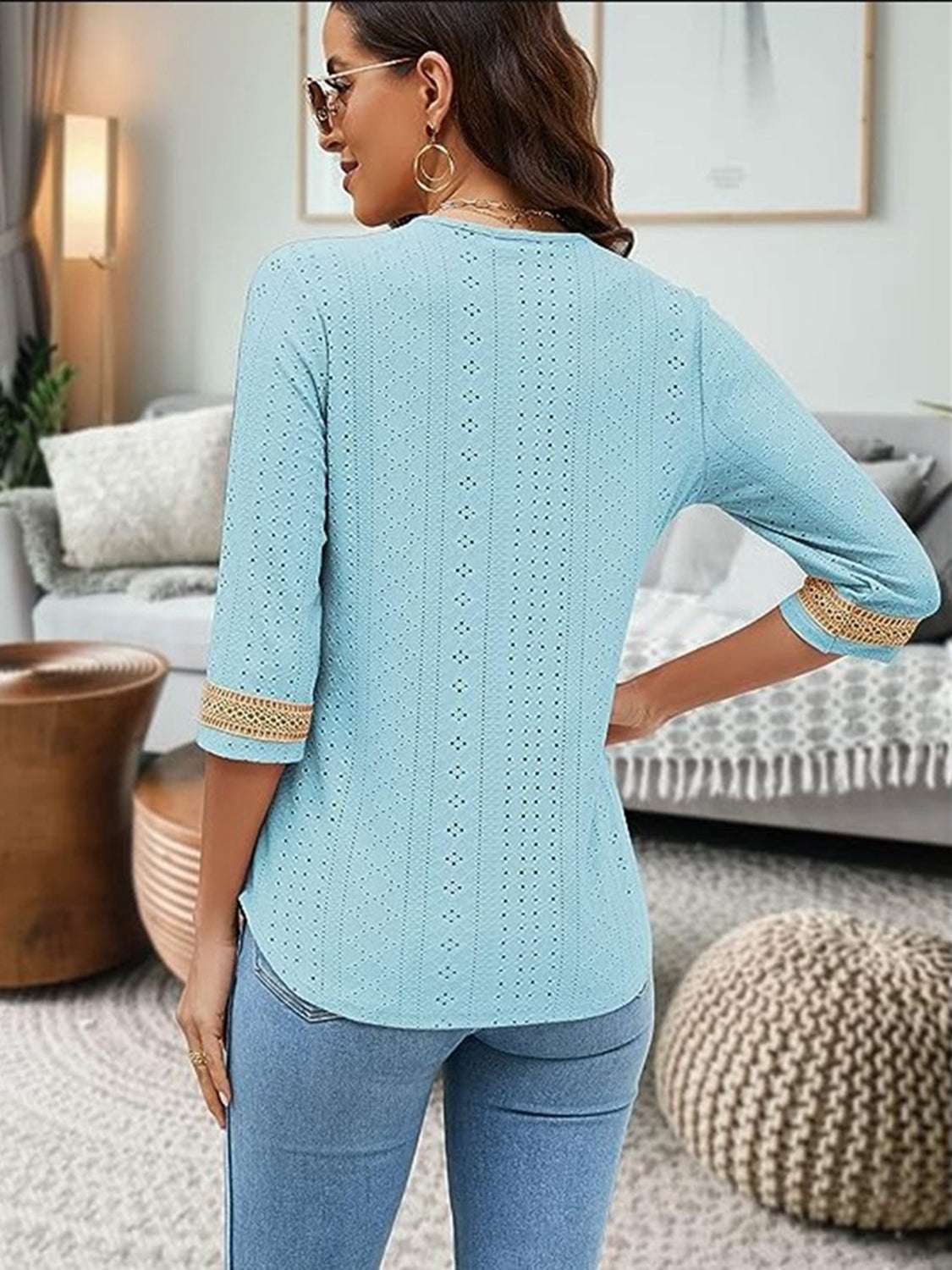 V-Neck Eyelet Blouse in light blue with 3/4 sleeves and crochet details, styled in a modern living room.