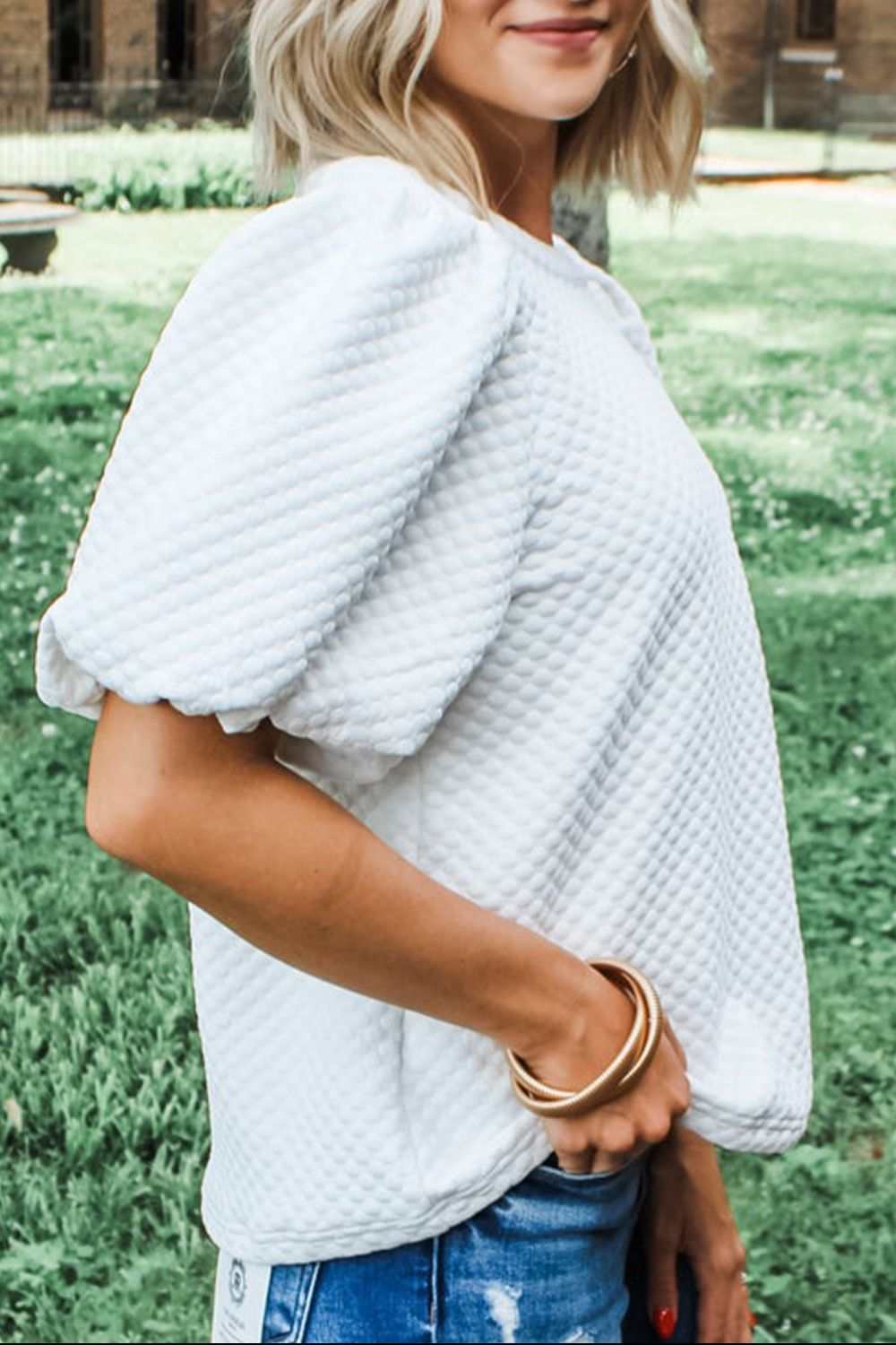 Textured round neck puff sleeve white blouse worn outdoors.