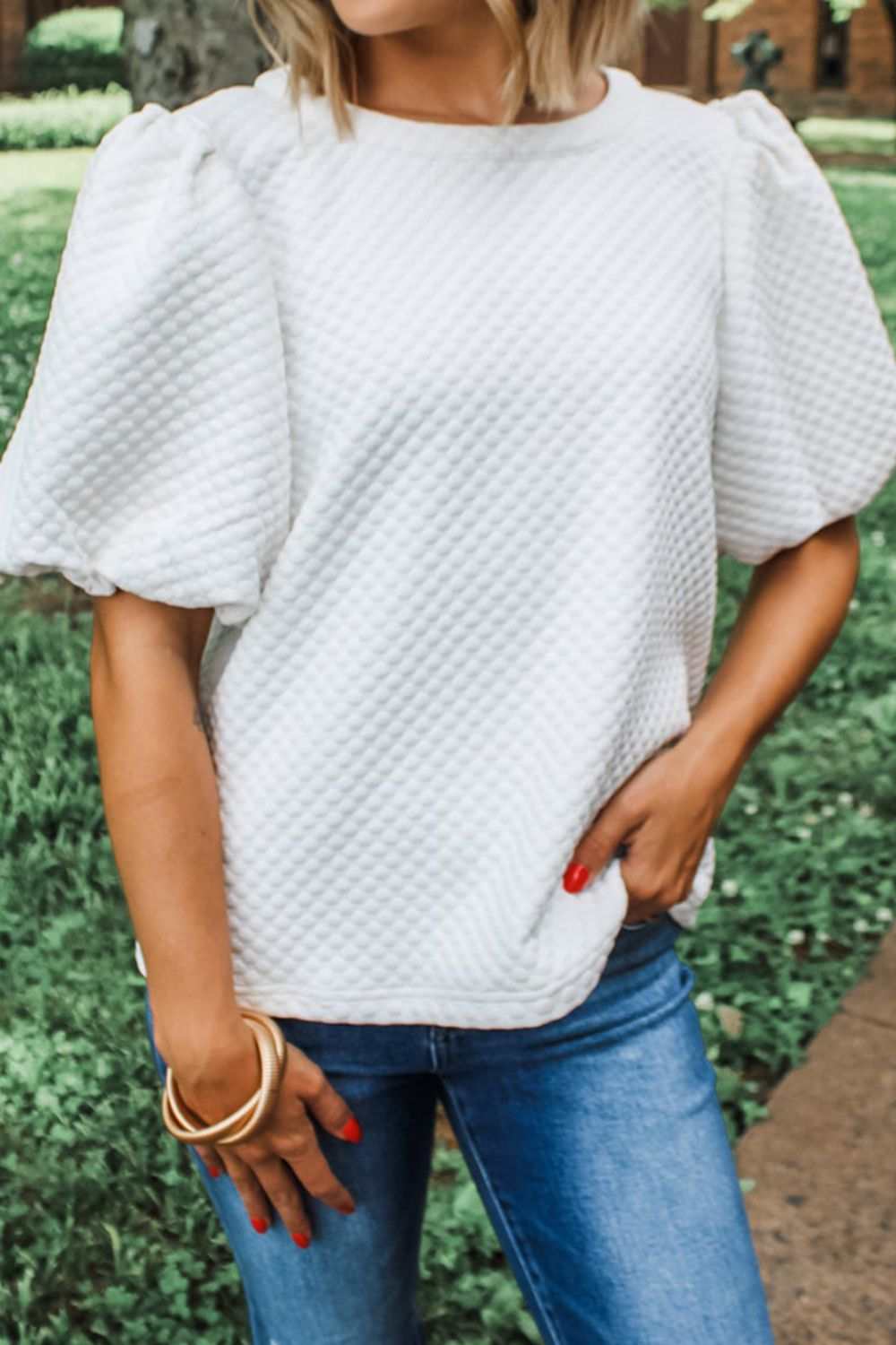 Textured round neck puff sleeve blouse in white, styled casually outdoors.