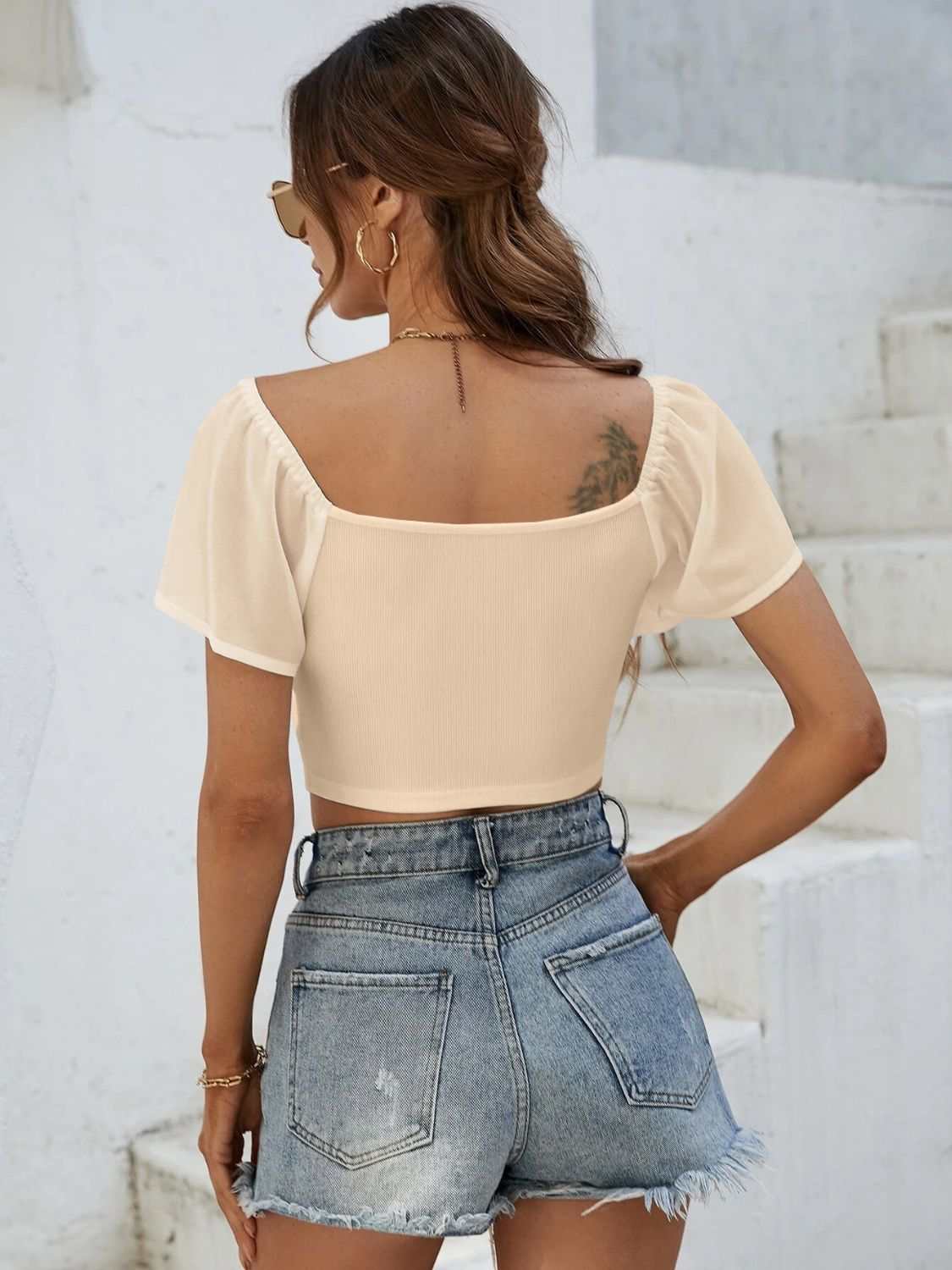 Women's drawstring short sleeve crop top, back view, paired with denim shorts.