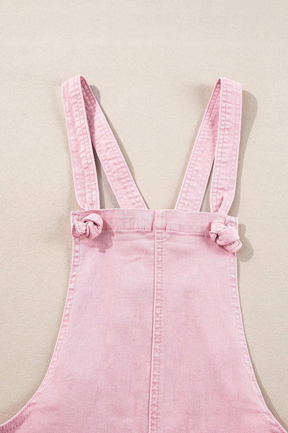 Knot straps denim overalls with pockets in pink.