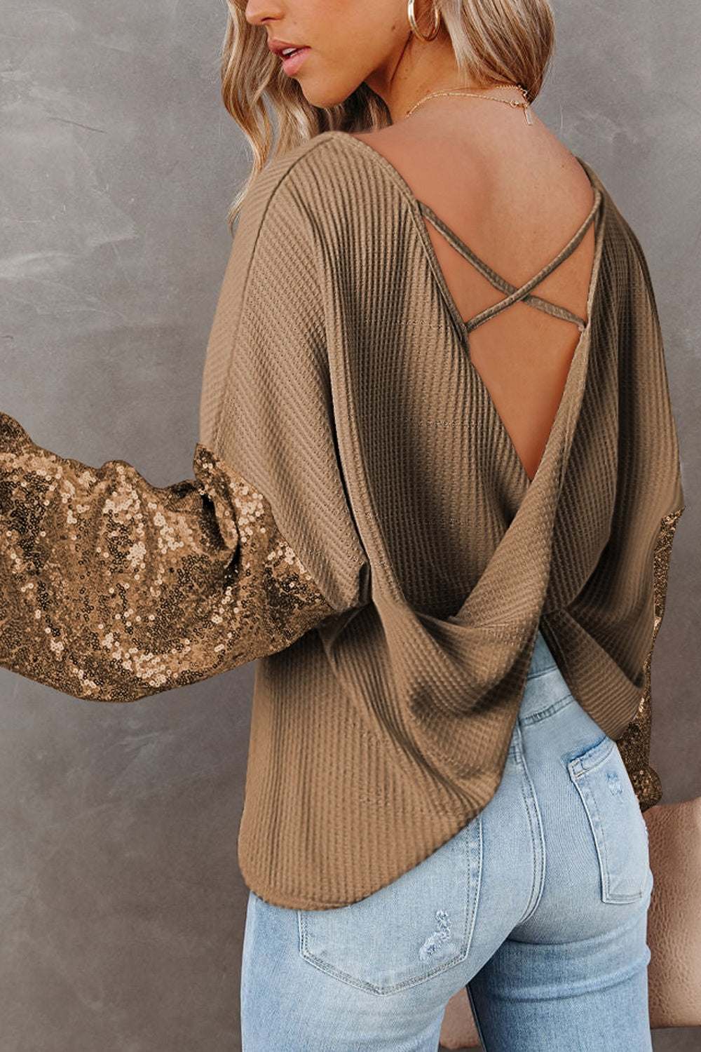 Sequin waffle-knit blouse with shiny sleeves and open-back design.