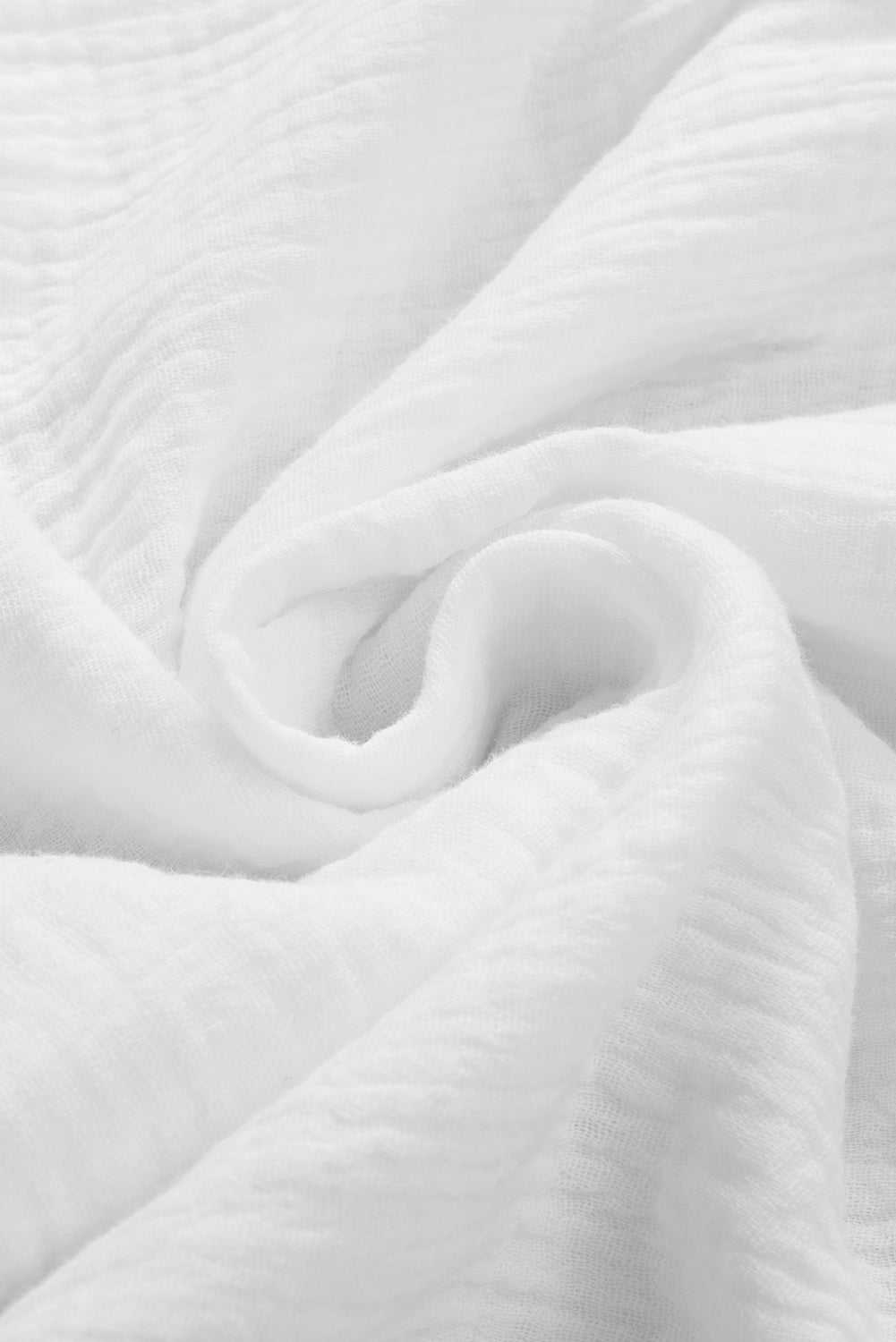 Solid white fabric of a dropped shoulder V-neck blouse made from 100% cotton.