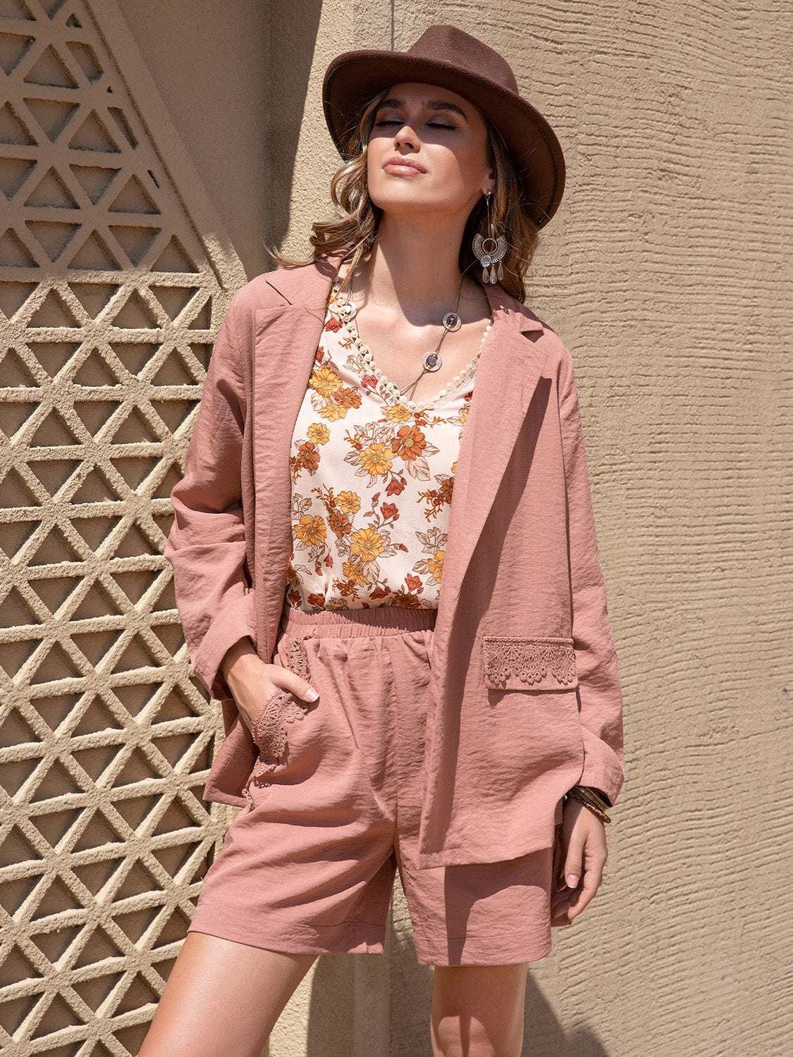 Woman wearing lace detail collared neck long sleeve top and matching shorts set in dusty pink with pockets and floral inner top.