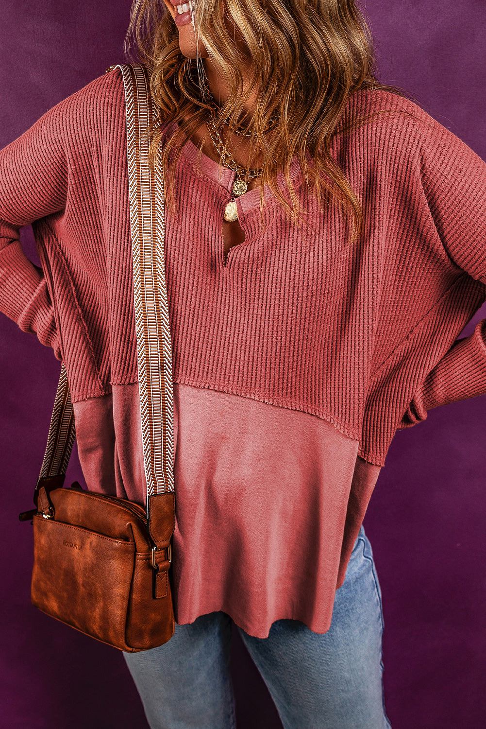 Notched neck long sleeve slit blouse in a two-tone design with slightly stretchy fabric, worn by a model paired with a brown bag.