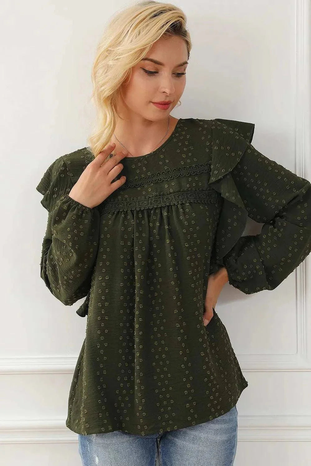woman wearing dark green round neck ruffled blouse with swiss dot pattern and long sleeves