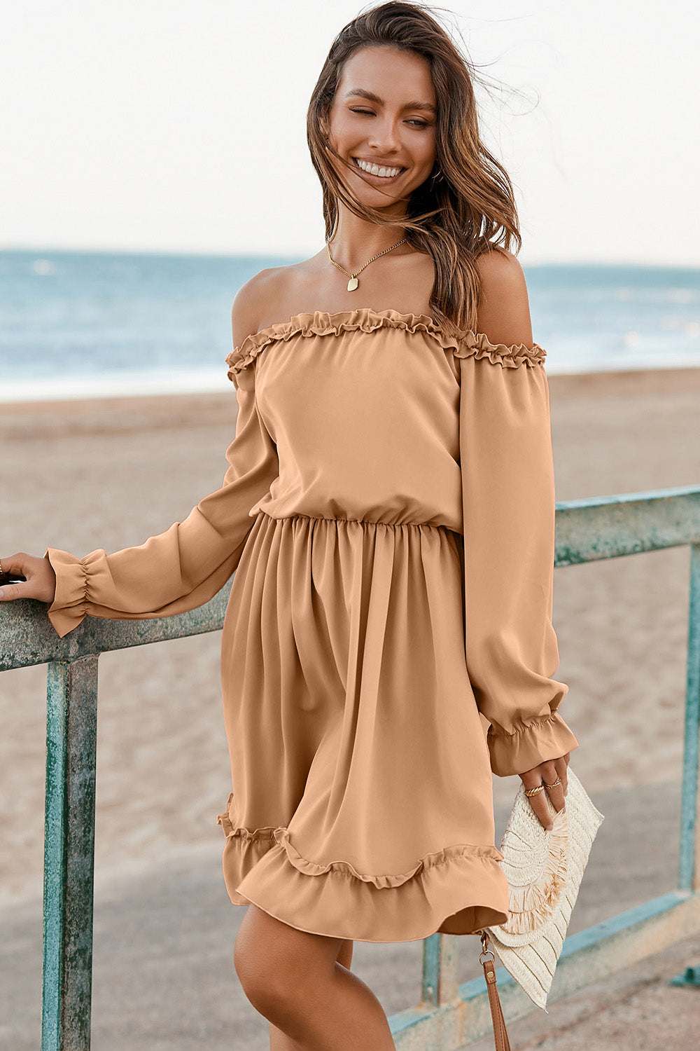 Frill off-shoulder flounce sleeve dress in beige on woman by the beach.