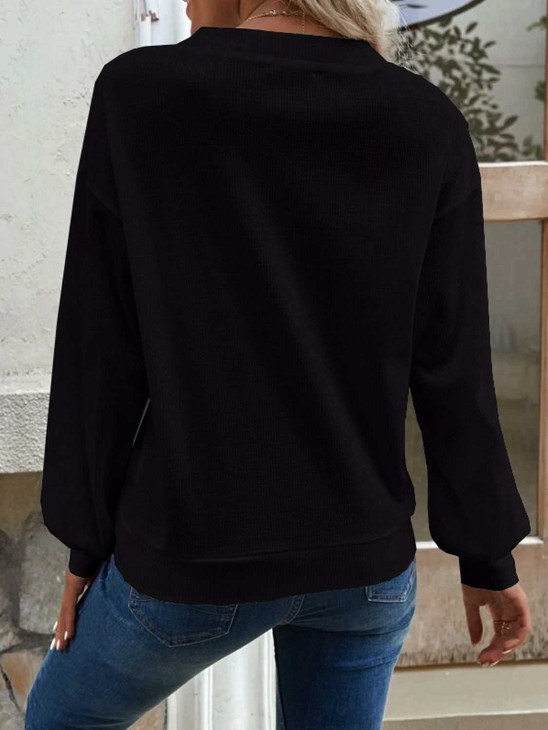 Solid black V-neck dropped shoulder blouse with waffle-knit texture and long sleeves.