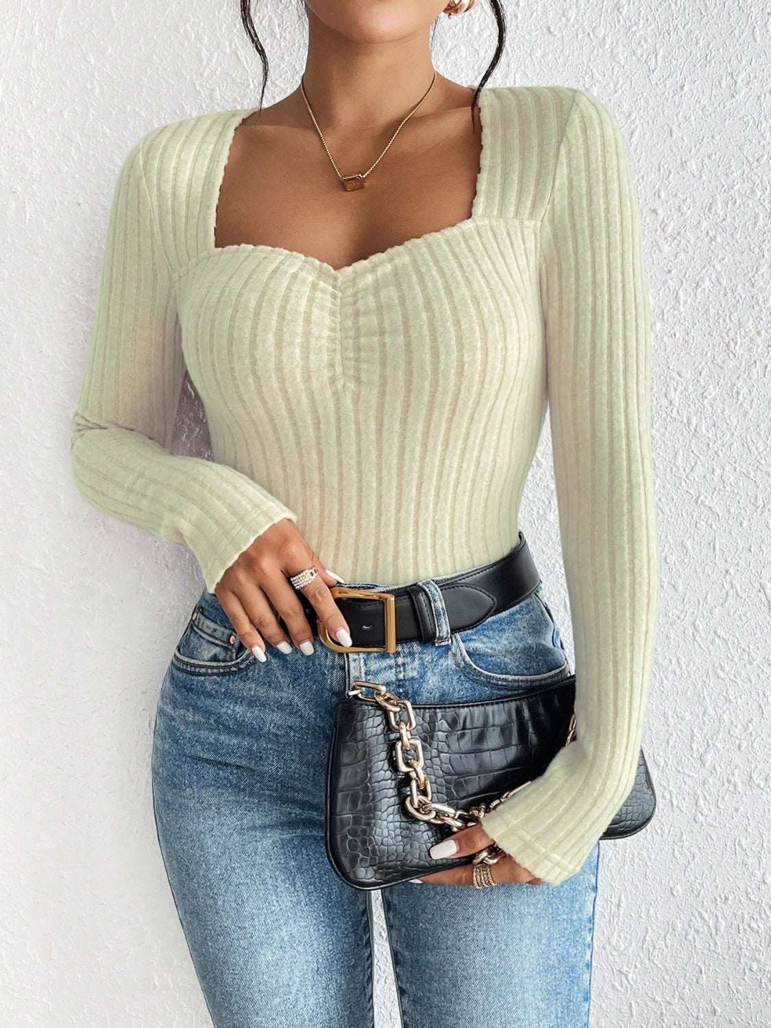 Honey ribbed long sleeve t-shirt in light color, paired with jeans and a black belt, showcasing a stylish neckline.
