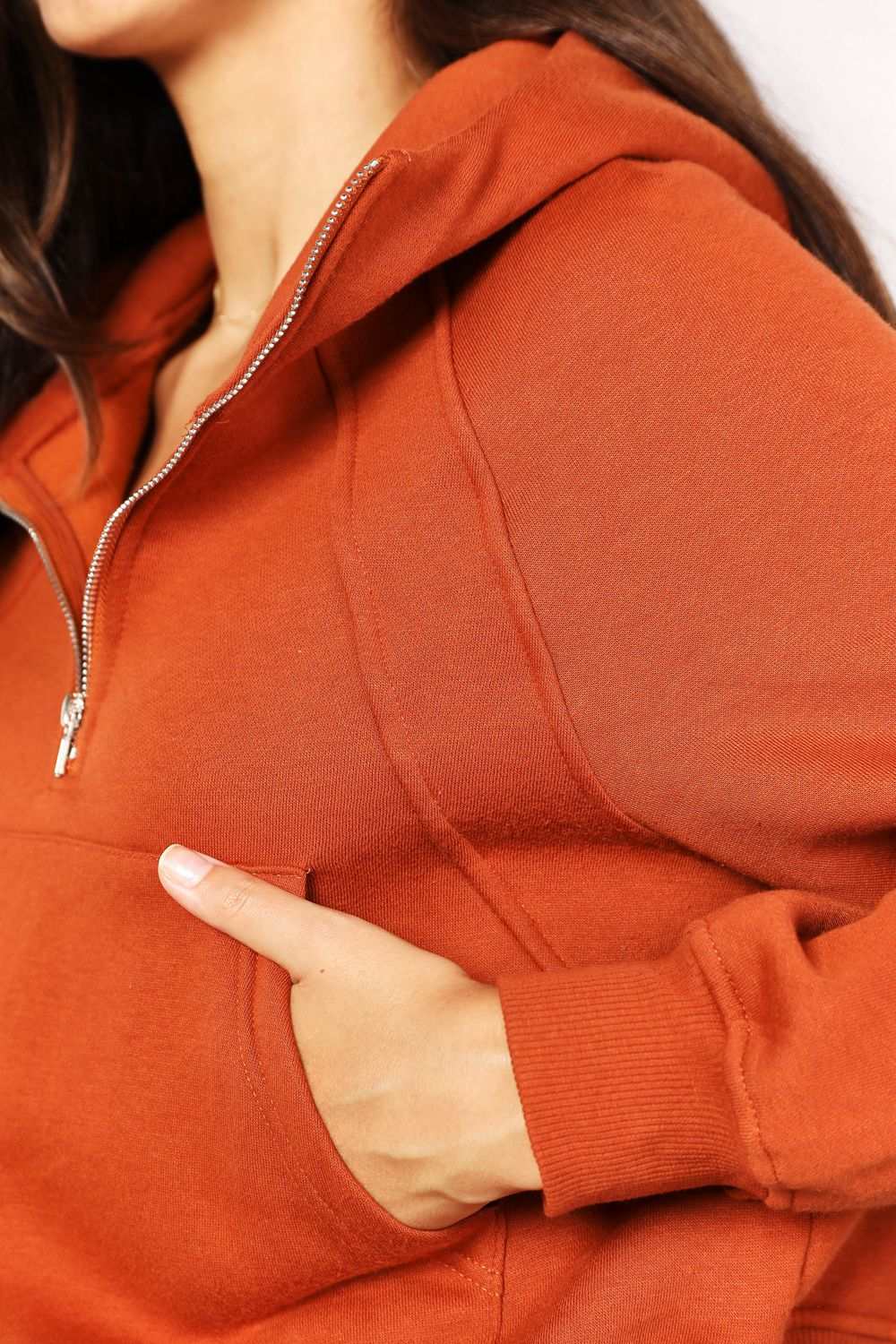 Solid-colored hoodie with half-zip design, ribbed long raglan sleeves, and collared neckline.